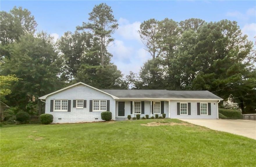 This charming brick ranch, situated in the highly sought-after East Cobb Wheeler School District, offers a welcoming blend of comfort and style. Step inside from the inviting covered front porch to discover a beautifully maintained home with a bright, open floor plan—perfect for entertaining. Gleaming hardwood floors flow seamlessly from the cozy family room, complete with a fireplace, into the sunlit dining area at the heart of the home. The spacious kitchen is a chef's dream, featuring stainless steel appliances, elegant marble countertops, and a custom tile backsplash. Retreat to the private owner's suite, which boasts an ensuite bathroom with a stunning subway tile shower. Two additional bedrooms share a hall bathroom equipped with a double vanity, providing plenty of space for family or guests. The converted garage, featuring a large walk-in closet, offers flexibility as a potential fourth bedroom, bonus room, or home office. Step outside to the tranquil, tree-lined backyard, perfect for relaxing or hosting gatherings. The deck, storage shed, and firepit patio create an ideal outdoor living space. This home is conveniently located just minutes from The Battery, Historic Marietta Square, Chattahoochee River National Park, and offers easy access to I-75. Don't miss this exceptional opportunity to enjoy modern living in a prime location!