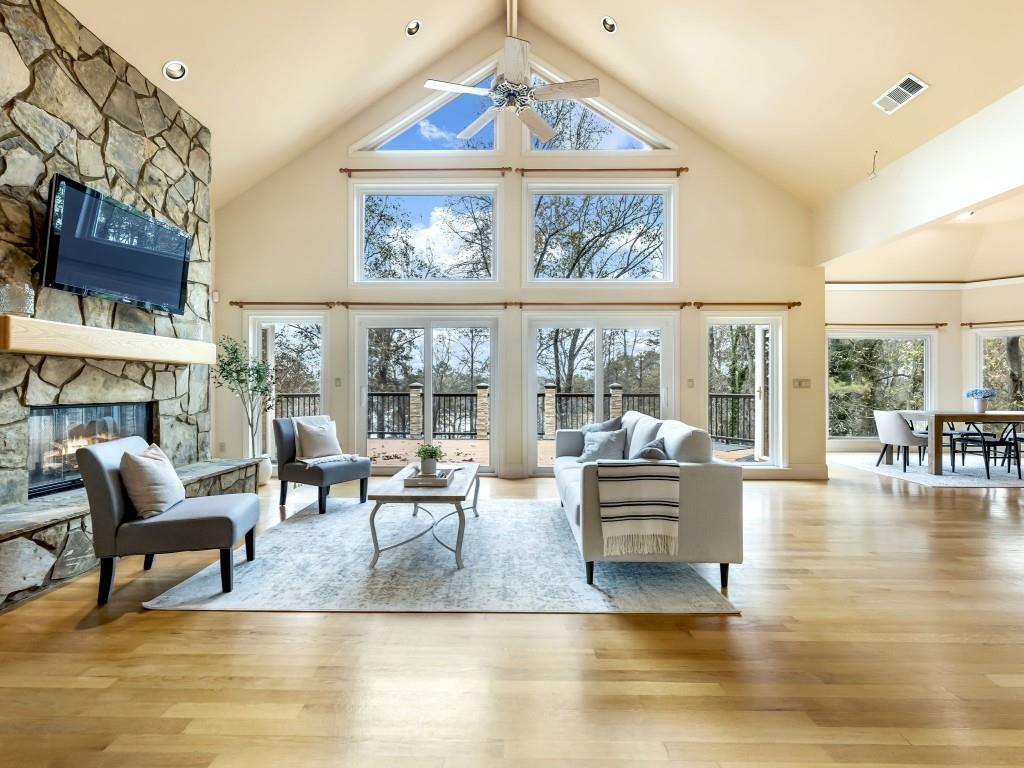 Whether you are ready to achieve the luxury of lake living or have been looking for the perfect vacation home, your search stops here. This Lake Lanier ranch has everything, except for an HOA! As you enter, you are greeted by stunning hardwood floors and floor-to-ceiling windows facing the lake. The open concept floor plan allows for breathtaking views from the living room to the kitchen. The kitchen features gorgeous hardwood cabinetry, granite countertops and a large island - ideal for entertaining large groups or day-to-day living. The spacious breakfast area allows for additional dining is complemented by a bay window view of the lake. The vaulted ceiling in the living room and stone fireplace provide the ambiance of a true lake home, while the open concept gives freedom for entertainment and gatherings. Off of the kitchen, step onto one of two huge decks and enjoy any season. The primary bedroom feels like a private escape within your own private oasis. With bay window views, a fireplace, a spacious en suite with double vanities, and its own screened in porch, you can experience relaxation at its finest. The main level also features two additional sizable bedrooms, one with en suite and a handicap accessible shower. The full, finished basement offers a large living/entertainment area with a floor-to-ceiling stone fireplace. The wood beams, recessed lighting, and profusion of windows are the perfect accents for true lake living. The large fourth bedroom is located in the basement and includes a full bathroom with double vanities, ideal for an in-law or teen suite. Just off of the basement is the covered second deck with dual fans, perfect for enjoying Georgia's hot summer nights. Take a short stroll through your back yard to your 2-story dock! Store and access your boat with ease. The slip last stored a 28 ft. Regal and contains a hydro hoist boat lift for one boat. This home has been very well-maintained and with a new HVAC and new roof, it is completely move-in ready! It has everything to offer whether you are dreaming of the luxurious lake life or if you are ready to invest in a fantastic vacation rental!