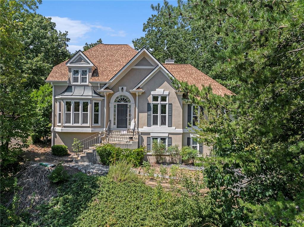 Nestled high on a hill, this home offers unmatched privacy and panoramic views. A long private driveway provides a grand sense of arrival while setting the home apart as a true retreat. Hardcoat Stucco 5-Bedroom, 4-Bath home with primary suite and secondary bedroom on the main level in the sought-after swim/tennis Highland Pointe community and award-winning East Cobb schools. The main level features a two-story foyer flanked by the dining room and a guest bedroom/office with access to a full bath. The spacious eat-in kitchen opens to the two-story fireside family room with direct access to the backyard patio. The large primary suite, featuring two closets and an ensuite bath, completes the main level. Upstairs you’ll find two generous bedrooms that share a renovated full bath. The terrace level offers an additional bedroom, a full bath, and a steam room. Recent updates include: roof (2022), two newer AC compressors (2019 & 2022), water heater (2023), and newer windows. The garage is equipped with a Tesla charging station. The private terraced backyard is perfect for peaceful enjoyment or gardening. Highland Pointe is part of the top-rated East Cobb school district, including Davis Elementary, Mabry Middle, and Lassiter High School. Community amenities include an Olympic-size swimming pool, kiddie pool, clubhouse, four tennis courts with pavilion, two scenic lakes, playground, picnic area, fitness center, sauna, and miles of hiking trails, basketball court, and all-purpose sports field.