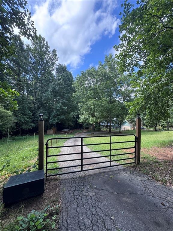 The mini-farm life awaits you in Loganville! This 1.5 acre property is loaded with character! From the moment you drive through the gate you will be greeted by a long driveway leading to the huge detached garage and inviting metal-roofed farm house with a large covered front porch. The home is flanked by 4 different penned areas (currently housing pigs, chickens, dogs and goats); the entire property is secured by electric fencing and backs up to a low lying creek. Inside the home you will be welcomed with gorgeous hardwood floors and wooden ceilings, a cozy yet open floor plan and gorgeous fireplace with wood burning stove in the living room. The oversized kitchen features butcher block countertops with a view to the sun room. Upstairs is an open, multi-purpose loft area, the primary suite with 2 walk-in closets and cozy bathroom, a secondary bedroom and full bathroom/laundry room combo and as an added bonus, the HVAC system is BRAND NEW! The large yard invites endless opportunities to give your "green thumb" a try or just to escape in your s/he shed (or workshop). This is a very unique property looking for new owners to love and care for it and make their dreams come true.