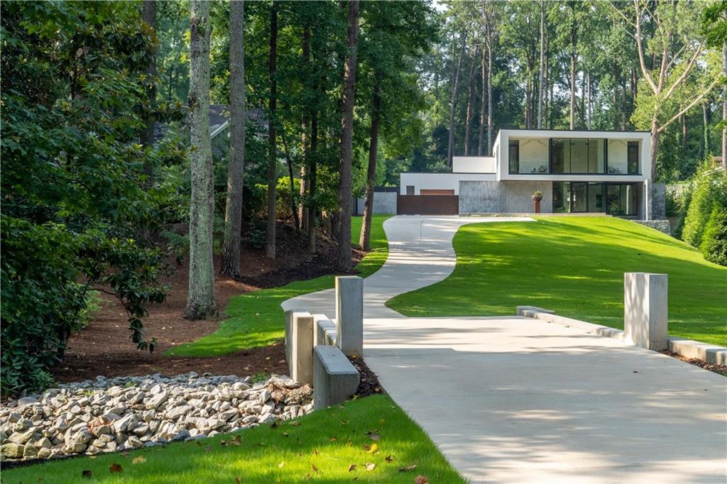 This listing is more than just another house to hit the market. This residence is an Experience- A Way of Life. If you’re looking for a Peaceful, Tranquil home with clean lines, beautiful views, and privacy on over 1.5 acres- this is it. Outstanding location close to many cultural and social hubs with easy access to the airport. Extraordinary Custom-Built modern residence designed by Jeffrey Bruce Baker. Features a 10+ backyard oasis with a sun ledge heated pool, raised black glass infinity spa & free-standing pool bath cabana. This spectacular home enjoys gentle sounds of water from the reflection pond with 2-story glass wall & glass pivot front door. The centerpiece of this house is the large great room with 20ft ceilings, dramatic Granite & Steel floating fireplace, 6-paneled sliding glass doors- seamless indoor/outdoor livability. Gourmet kitchen features a Butler’s pantry with stone door, custom cabinetry, separate prep area, Compac counters & stone slab-clad walls overlooking the outdoor eating area with a screen & fireplace. Rare, master on main, enjoys access to the pool, opulent, oversized closet & dressing room with custom cabinetry & many storage spaces. The master suite bath enjoys multi layers of white materials/textures for a sleek look. Attached in the master suite is a separate office designed for maximum function & efficiency. Also on the main level is a media room/den/library & home gym. The second level features 3 guest suites-2 enjoy balconies with front yard views. Plus separate hangout TV area & rooftop terrace that overlooks the backyard. Other innovative & design features include a dramatic floating double staircase, Neolith porcelain, three-coat cement stucco facade, Pella windows, oversized 3-car garage & motor court with custom power gate. Featured in Architectural Digest Oct. '21 Issue! Be sure to check out the video.
