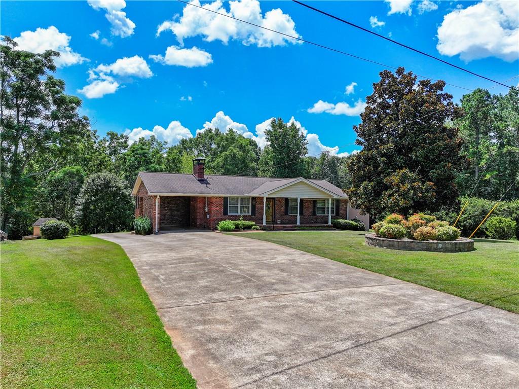 100% USDA Financing Eligible! Right in the heart of Hall County’s top school district, this charming brick home offers the perfect blend of comfort, character, and convenience. From the inviting front porch, you can take in beautiful mountain views. The spacious, level yard boast a brand new, underground dog fence and is surrounded by mature trees and lush shrubbery, creating a perfect space for kids and pets to play. The expansive backyard is perfect for entertaining, with plenty of room for outdoor gatherings. A fenced-in pool area (now filled in) provides potential for your personal touch. In addition, a large workshop in the backyard offers ample storage space for tools and equipment, while a separate pull-in area is perfect for lawnmowers or other outdoor gear. Inside, the living room features a cozy rock-faced fireplace and warm wood walls, creating a welcoming atmosphere. The wood cabinetry throughout adds rustic charm to the interior. Located just 3 miles from the North Hall Community Center and a variety of great restaurants, this home offers the best of both quiet living and easy access to local amenities.