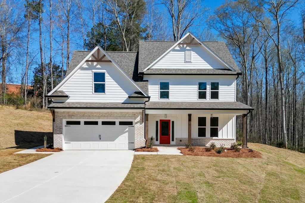 Contemporary craftsman-style residence featuring white siding, a contrasting dark roof, and a red entry door