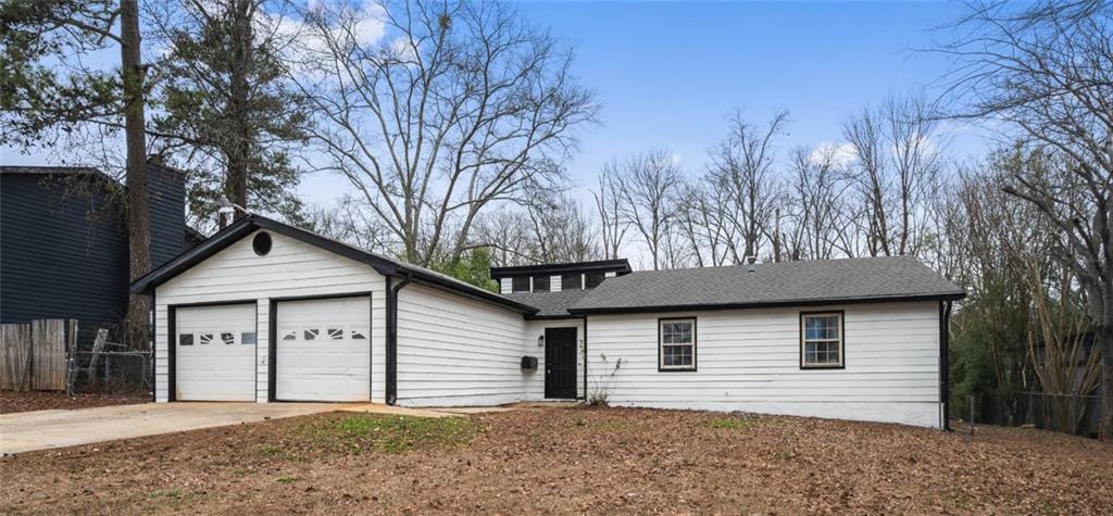 Ranch-style house with a garage and roof with shingles