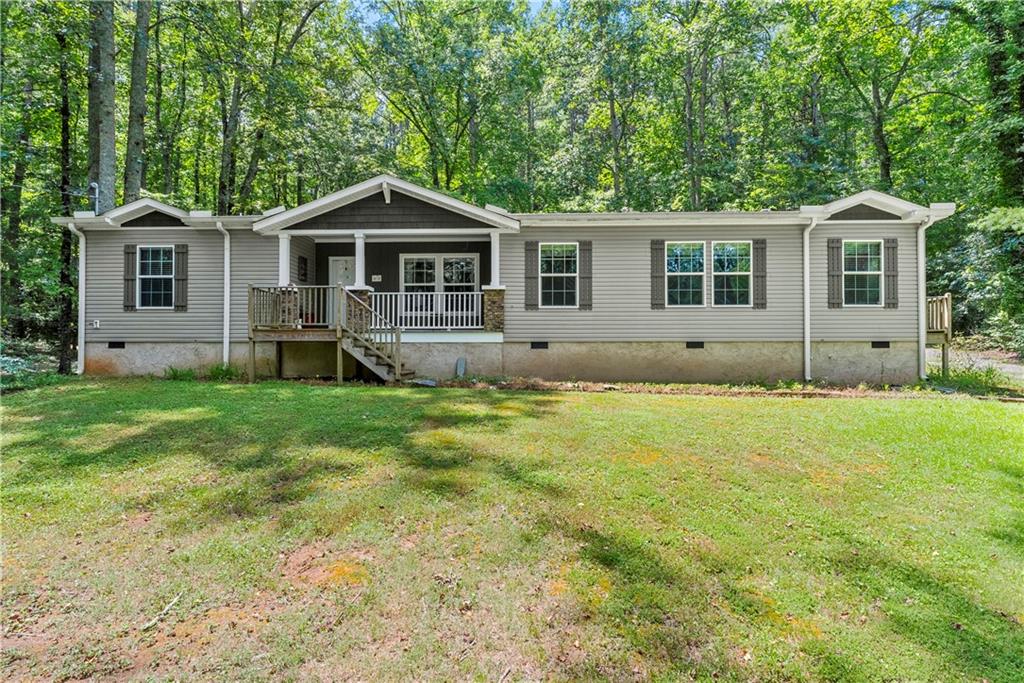 Welcome home to this meticulously well-maintained 3 bedroom, 2 bathroom manufactured home sitting on a permanent foundation! Situated on one level acre of land in the highly desired Sequoyah District, this home has NO HOA and plenty of wooded privacy! Bring your RV or outdoor toys! Over 1900+ SQ FT, inside, you will find an open concept, main living area featuring wooden beams and a gas log fireplace. Just off the family room is your spacious kitchen/dining area featuring a large island and stained kitchen cabinets. Your primary suite is over-sized and offers his/hers separate walk-in closets and vanities! Enjoy soaking in your garden tub while enjoying the nature views! On the other side of the home, you will find two secondary bedrooms with large walk-in closets as well as a secondary bathroom. Quick and easy access to East Cherokee Dr; Hwy 5; Hwy 575 - just minutes to all the shopping and dining of Canton, Woodstock or Hickory Flat! FHA and VA approved! Come tour this home today!
