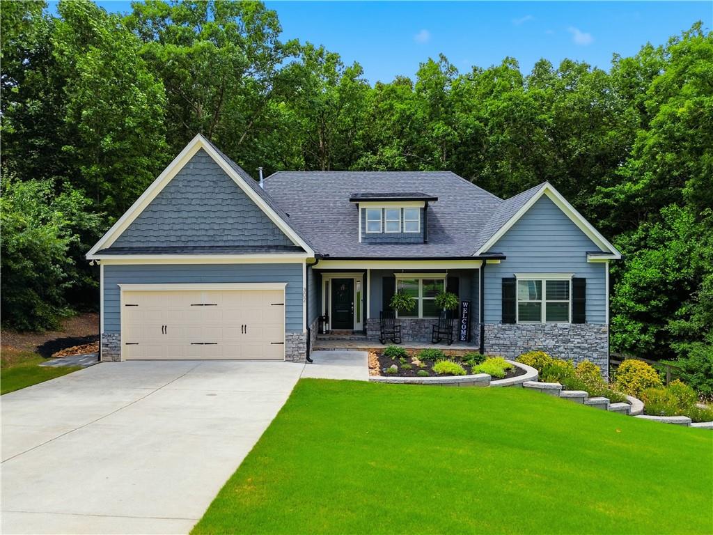 Blue siding home with gray stone accents, a concrete driveway, and a two-car garage