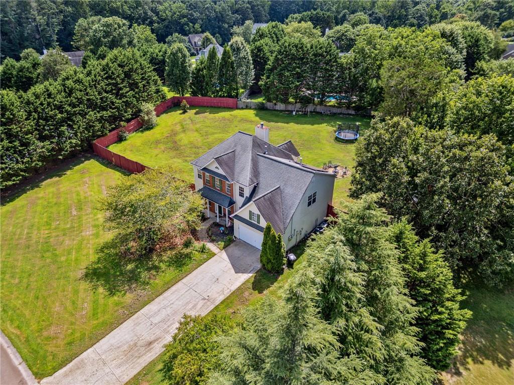 This home is not only move-in ready but is also equipped with energy-saving solar panels! This 5-bedroom, 3-bath home is nestled on just under an acre in the sought-after Holly Trace neighborhood. This spacious home is designed with you in mind, offering flexible living spaces, a fenced yard, and the added value of solar panels for reduced utility costs and sustainable living. Inside, you'll find fresh interior paint in many of the rooms and a functional layout featuring a large family room with fireplace, a separate dining room, and a bonus room on the main—perfect for a guest suite, home office, or playroom. The kitchen offers plenty of cabinet space, a breakfast area, and a view of the family room, ideal for both busy mornings and evening gatherings. Upstairs, the oversized primary suite includes a walk-in closet and a private bath with double vanities. Three additional bedrooms and a full bath, also upstairs, are all good-sized. Outside, enjoy a level, fenced backyard that’s ready to be enjoyed by all, plus a powered outbuilding for extra storage or workshop use. With a 9-year-old roof, low HOA, and an ideal location just minutes from Canton, Cumming, and Milton, this home delivers both convenience and value. Move-in ready, family-friendly, and equipped with solar power —don’t miss your chance to make this Ball Ground gem your next home.