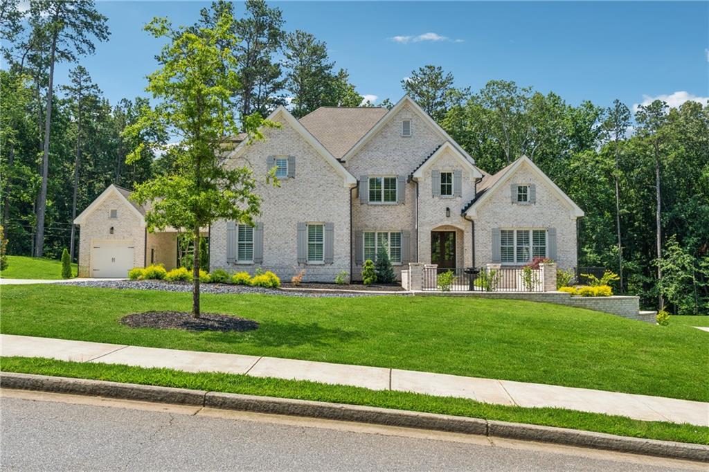 Nestled on two private acres in the coveted Breamridge community, this stunning four-sided brick estate invites you to experience the very best of Milton living—where timeless craftsmanship, luxurious finishes, and thoughtful design come together effortlessly.
From the moment you arrive, the home’s classic elegance makes an impression. A Porte-cochère connects the main home to the detached fourth-car garage, enhancing both the curb appeal and functionality of the residence. Whether you're hosting a grand gathering or returning home after a long day, this gracious entry sets the tone for what lies beyond.
Inside, natural light floods the soaring two-story foyer, where warm white oak hardwood floors guide you through an open and airy layout. The main level offers a bright formal living room or home office, a generous dining room perfect for special occasions, and a luxurious primary suite with peaceful views of the backyard—ready for a future pool or enjoyed as-is.
At the heart of the home, the chef’s kitchen blends beauty and function. Outfitted with double ovens, a built-in refrigerator, a hidden walk-in pantry and a large island ideal for prep or casual dining, the kitchen flows effortlessly into both the main living room and a cozy keeping room—a perfect spot for morning coffee or evenings by the fire.
Upstairs, four oversized secondary bedrooms each feature custom wood-shelved closets and private en-suite bathrooms, offering space and privacy for all. A large unfinished basement provides endless potential for future expansion or personalization.
Step outside, and you’ll find a true outdoor sanctuary. The covered patio extends to a fully equipped built-in kitchen with grill, refrigerator, sink, and pizza oven—ideal for hosting friends and family year-round. Two outdoor dining areas, a cozy fire pit, and lush landscaping complete the perfect setting for entertaining or quiet evenings at home.