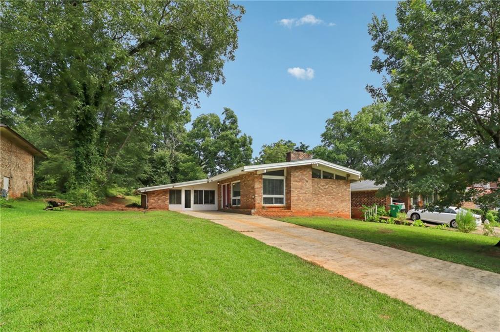 Midcentury character meets modern comfort at 2428 Parkland Drive. This 3-bedroom, 2-bath home with bonus room is a striking example of Frank Lloyd Wright-inspired architecture, with vaulted ceilings, exposed beams, and walls of windows that flood the interior with natural light. Original hardwoods and preserved vintage tile blend seamlessly with thoughtful updates, creating a home that honors its history while feeling fresh and contemporary. The large bonus room adds flexibility for a home office, gym, or media space. Outside, the private backyard is designed for entertaining with a custom patio and garden retreat, perfect for gatherings or quiet mornings. Located in a peaceful residential pocket, the home offers quick access to Decatur, East Atlanta, and Grant Park. N.H. Scott Park is right down the street with tennis and basketball courts, green space, and a new pool underway. For buyers seeking style, space, and convenience, this home delivers. Bold architecture, modern updates, and a prime intown location make 2428 Parkland Drive a rare opportunity.