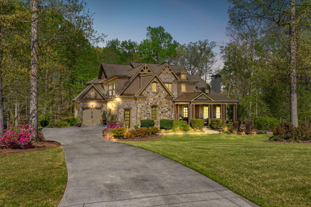 Welcome to this magnificent east-facing luxury estate in the prestigious The Springs of Chateau in Hoschton. This exceptional 6-Bedroom, 5.5-Bath residence boasts over 6,700 sq ft of expertly designed living space. Every detail of this exquisite estate has been thoughtfully executed, from the gleaming hardwood floors and intricate crown molding to the numerous fireplaces and extensive custom cabinetry found throughout. Upon entering, be captivated by the grand foyer, setting the stage for the warm and inviting atmosphere. The well-appointed Study showcases custom-built cabinets and a stunning stone fireplace providing a refined space for work or study. The soaring two-story Family Room adorned with a gorgeous stone fireplace is the heart of the home, perfect for gathering with family and friends. The stately Master Suite on the Main Level offers a sense of tranquility, featuring a cozy fireplace, coffered ceiling, custom built-in cabinets, and a spa-like ensuite Bath with a luxurious soaking tub and separate oversized custom shower. Inspire your culinary dreams in the gourmet Kitchen with abundant cabinetry, high-end stainless-steel appliances, a large center island, and the adjacent keeping room with a fireplace and great fireside chats. Venture upstairs to discover the Secondary Suite, with a walk-in closet and Spa Bath complete with a large shower and separate soaking tub. Two additional sizeable Guest Bedrooms, each with its own ensuite Bathroom and spacious closets, and a Bonus Room perfect for a Craft Room or second Home Office. The spectacularly finished Terrace Level is an entertainer's paradise, featuring a second Kitchen, 2nd pantry, Full Bathroom, elegant Dining Room, laundry, spacious Family Room, and two more generously-sized Bedrooms with enormous closets. The home's exterior is equally impressive, with its stately brick and stacked stone facade, and meticulously manicured landscaping all situated on a large, wooded cul-de-sac lot. Outdoor living spaces include a covered front porch, spacious rear deck, and a covered lower-level patio inviting you to relax outside and appreciate the serenity of your surroundings.