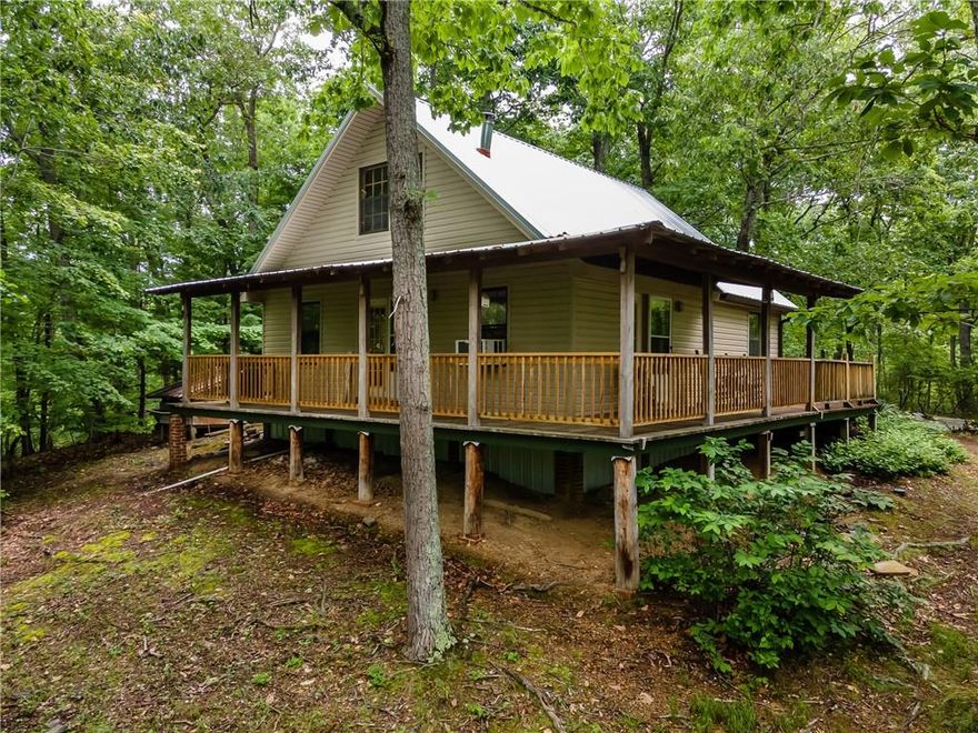 SELLER OFFERING $5000 toward closing costs or rate buy down!! Step back in time, to when life was simpler and more serene! This unique cabin is nestled on 11.95 acres, surrounded by majestic woods and nature's splendor. 2 bedrooms, 1 bath, and a loft area upstairs, perfect for relaxation. Mornings and evenings on the wrap-around porch will be a true delight, and the NEW metal roof is sure to make the rain more enjoyable. Enjoy the wood burning stove on those cold winter nights.  A 16x16 shop is also included, ideal for woodworking enthusiasts or extra storage. Take leisurely walks on the property, pick fresh blueberries, and enjoy the wildlife, including deer and turkey. Turn this haven into your own peaceful retreat or a thriving Airbnb! This property holds immense potential, waiting to be unleashed. Schedule a viewing today and discover all this property offers!