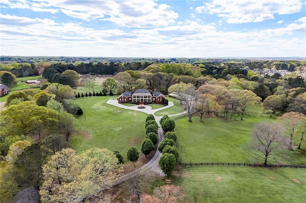 Experience luxury living at its finest with this unparalleled estate nestled in the heart of Forsyth County. Enter the estate through the private gates, drive along the beautiful driveway lined with Bradford Pear trees to the 15 meticulously manicured acres. This property stands as a testament to exquisite design and unparalleled craftsmanship. You'll be captivated by the charm of the four-sided brick Georgia Colonial home, boasting a majestic 50-foot front porch and balcony overlooking the scenic surroundings. A picturesque white gazebo graces the landscape by the stocked one-acre pond, offering a tranquil retreat for moments of reflection.
For wine enthusiasts, the property features a small vineyard cultivating the historic Lomanto Grape, with a water drip system sourced from the pond. Stroll through fenced pastures and discover a 2100-square-foot barn, thoughtfully repurposed to host gatherings with friends and family, complete with a covered patio. Perfect for hosting events. For the Equestrian Lovers, stalls can be placed back into the barn. Upon entering the foyer, adorned with marble floors and a signature staircase, you'll be greeted by grandeur at every turn. From the formal living room with its dual chandeliers and fireplace to the expansive dining room and cozy study with wood coffered ceilings, every space exudes elegance and warmth. Exquisite custom crown moldings and trim truly add to the attention to every detail of this elegant home. The sunroom offers a casual retreat, perfect for family to gather, while the chef's kitchen is equipped with top-of-the-line appliances, cooking island with 6 burner gas cook top, subzero refrigerator, think granite counters, wall oven with warmer, even a fountain soda dispenser. Numerous cabinets and a large Butler's pantry with an additional refrigerator allows for plenty of storage. Large informal dining area for hosting large family dinners. Oversized laundry room with chute from upstairs. central vacuum. The main level boasts an impressive primary suite with a separate sitting room, fireplace, three walk in closets and luxurious en-suite bath with his and her vanities, freestanding tub, bidet and double shower and steam shower! There is a secondary bedroom with large walk in closet and its own private bathroom. Also on the main you will find a private office with a great view, 3 car garage equipped with hot and cold water and icemaker. Take the elevator or one of the 2 staircases to ascend to the upper level, where you'll discover 4 oversized bedrooms, each with walk-in closets and private bathrooms, along with two expansive bonus rooms and a loft area leading to a sprawling balcony. The terrace level is designed for entertainment, featuring a recreation area, built-in bar, billiard area, family room, and additional bedrooms and bathroom. A hidden concrete safe room provides added security and peace of mind. Outside, a heated saltwater pool and raised spa beckon for relaxation, while a pavilion offers a full outdoor kitchen, bar area, fireplace, and cabana bath for alfresco dining and entertainment. Fenced pastures, a stocked pond, the vineyard, the barn, apple, peach, crabapple trees and blueberry bushes these 15 acres offer pure pleasure. With an automatic commercial generator that runs on the natural gas, central vacuum system, and to your convenience. Countless other amenities, this estate truly stands as a one-of-a-kind masterpiece. Schedule your private showing today and discover the epitome of luxury living in Forsyth County.