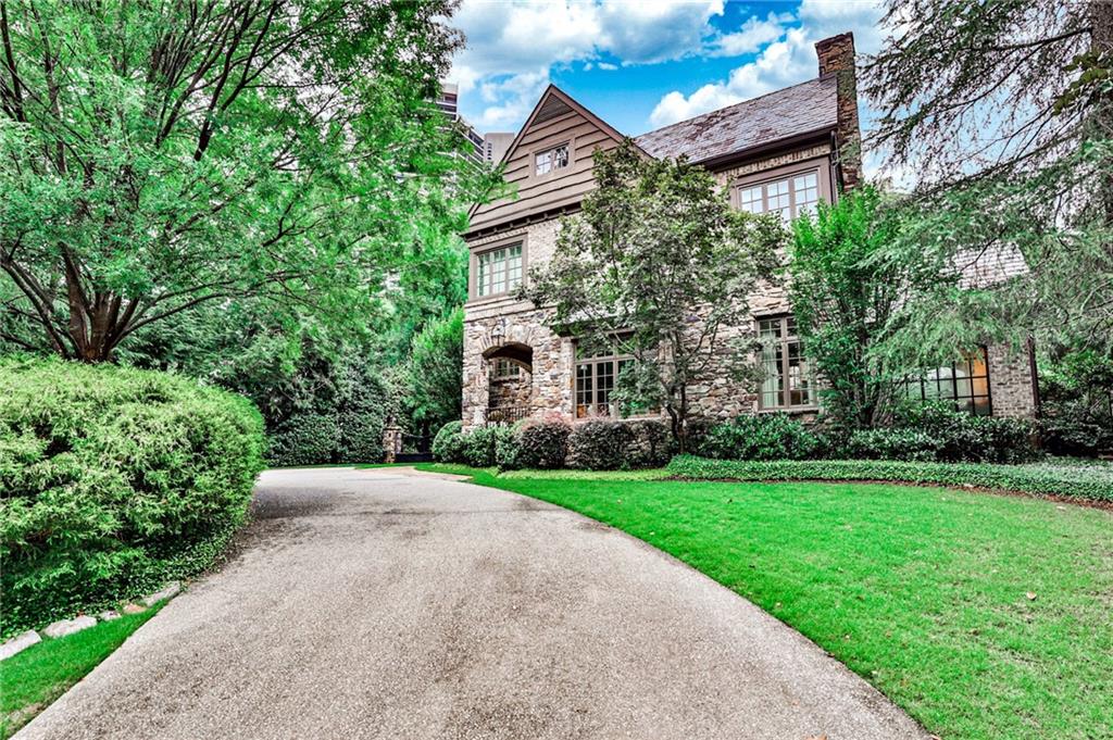 This one-of-a-kind home, designed by notable architect Yong Pak and builder Mike Hammersmith, and recently decorated by Kay Douglass, is nestled on a private, one acre hilltop lot. Stunning 15-year-old English country manor home blends old world charm with modern style with iron windows and doors, as well as old world finishes such as plaster walls, stunning five-inch white-oak floors, and handsome handmade white-oak beams. The exterior of the home is topped with a Ludowici 150-year slate roof, copper gutters and flashing, and a tasteful exterior mix of stonework and old brick. The three-car garage has been finished with epoxy floors and custom cabinetry allowing it to double as event space, ideally located next to a flat turf sports field and putting green.
The open floor plan and soaring ceilings on the main floor give the home a flawless flow throughout and include a wet bar, butler’s pantry, china closet, family room, breakfast room, dining room, living room, sunroom, and mudroom, as well as two half baths. The open concept kitchen boasts cabinetry by Stile, marble countertops, Viking appliances, double refrigerator and dishwasher drawers, two full sinks and a large island overlooking the family room. These lovely rooms wrap around a private courtyard with Gunite pool and cozy outdoor covered seating area with fireplace and overhead heating.
The second-floor master suite includes cathedral ceiling, fireplace, and Juliet balcony overlooking the pool. His and her marble bathroom is outfitted with soaking tub, separate vanities, separate water closets, and heated floors. Included on the second floor are three ensuite bedrooms with walk in closets and an additional seating area and a large laundry room with custom cabinetry. There is a separate in-law/au pair suite with a small kitchenette, and cozy den, ideally situated over the garage with a separate entrance and a staircase chair system for handicapped access which can easily be removed. There are permanent stairs up to a third floor which has been plumbed and framed for two more bedrooms and two more baths or a huge playroom.
Lower floor can be accessed down a staircase from the main floor or thru an exterior entryway. It is finished off with a large mirrored and fully outfitted workout room with rubber flooring, as well as a large media room, an additional half bath, and multiple storage areas.