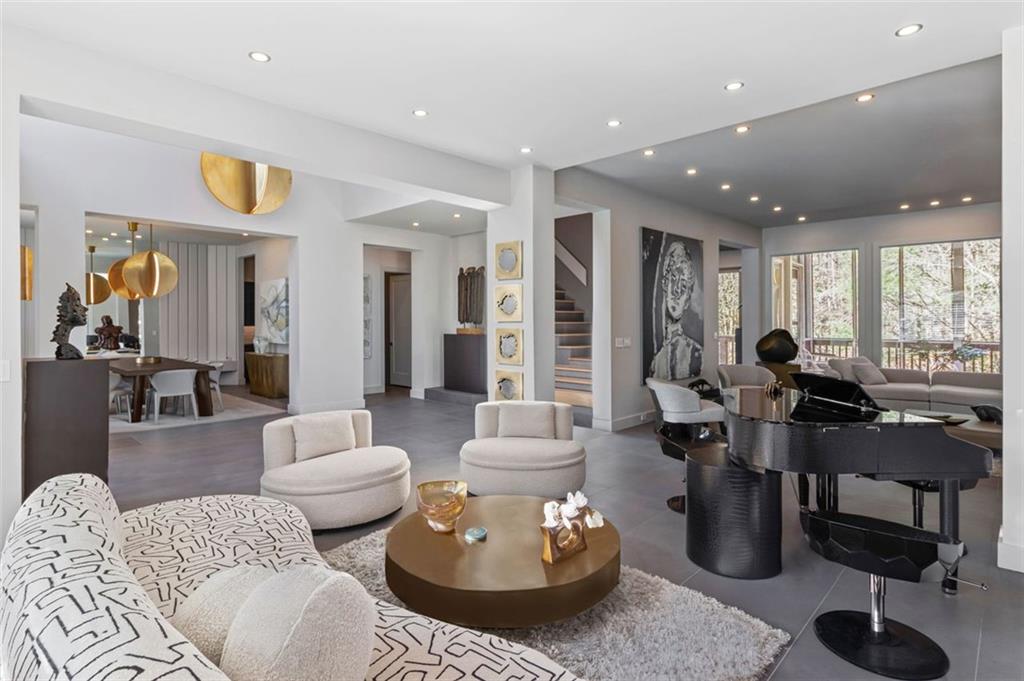 A true architectural marvel, this home was meticulously curated by the internationally acclaimed Faytak Designs, founded by visionary designer Faye Takaloo. Since 2009, Faytak Designs has set the gold standard for opulent living, transforming elite spaces across Atlanta, Los Angeles, London, and Dubai into breathtaking sanctuaries where elegance meets functionality. Now, that same level of world-class sophistication graces this exceptional residence. Step through custom double iron doors into a stunning foyer where sleek gray porcelain slabs and an awe-inspiring Italian chandelier immediately set the tone for refined elegance. Straight ahead, a sculptural staircase—a work of art in itself—ascends gracefully, while a curated art installation at its base adds a touch of intrigue. To your left, the dining room dazzles with a sophisticated mirrored and wood-paneled accent wall that blends glamour with warmth, creating the perfect setting for memorable gatherings. The original family and living rooms have been seamlessly combined into an expansive entertainer's dream, where form and function harmonize effortlessly. Anchoring this impressive space is a crocodile-motif Fendi piano—a statement piece that exudes opulence. Thoughtfully curated décor and avant-garde design elements elevate the atmosphere, making this home as livable as it is visually stunning. The heart of the home, the kitchen, is a culinary masterpiece where no detail has been overlooked. Custom soft-close cabinetry, pristine quartz countertops, and top-of-the-line appliances, including a Sub-Zero-style cabinet-front refrigerator, double French ovens, and a 6-burner Viking gas cooktop with a pasta faucet, ensure that this space is as functional as it is breathtaking. Whether hosting intimate dinners or grand celebrations, this kitchen delivers a seamless blend of elegance and utility. On the main level, a generously sized guest suite offers the perfect retreat, complete with an updated ensuite bath—ideal for visiting family or as a refined home office. Upstairs, the primary suite is a sanctuary of tranquility, featuring a cozy sitting area adorned with a fireplace, custom bookshelves, and a built-in bench. Step out onto your private deck to savor morning coffee while overlooking the impeccably manicured, fenced backyard. The spa-inspired primary bath elevates daily routines with its modern freestanding tub, oversized shower, bidet, and artistic paneled accents—transforming every moment into an indulgent escape. Porcelain floors extend across both levels, creating a continuous flow that enhances the home’s architectural beauty. A 3-car side-entry garage is equipped with 2 EV charging stations, ensuring that modern convenience complements the luxurious lifestyle this home offers. The fully finished terrace level is a haven of entertainment and relaxation, designed to meet every need. This space includes: A secondary kitchen and dining area for effortless hosting, a stylish TV room for casual lounging, a state-of-the-art theater room for immersive cinematic experiences, home gym to keep wellness goals within reach, and private spa with a full bath, offering the ultimate space for rejuvenation. An additional guest suite with its own bath provides privacy & comfort for overnight visitors, ensuring that every guest feels at home. Renowned for transforming properties to resonate with discerning buyers, Faytak Designs brings its signature staging expertise to this estate, ensuring maximum return on investment and minimal time on the market. Every inch of this home reflects Faye Takaloo’s philosophy of “ultimate luxury,” blending timeless elegance with cutting-edge innovation to create a residence that is truly without equal. Located near scenic trails, and just minutes from one of Roswell’s award-winning parks. Seller is offering a discounted rate of 5.75% 7 Year ARM with a 10k lender credit through the sellers preferred lender
