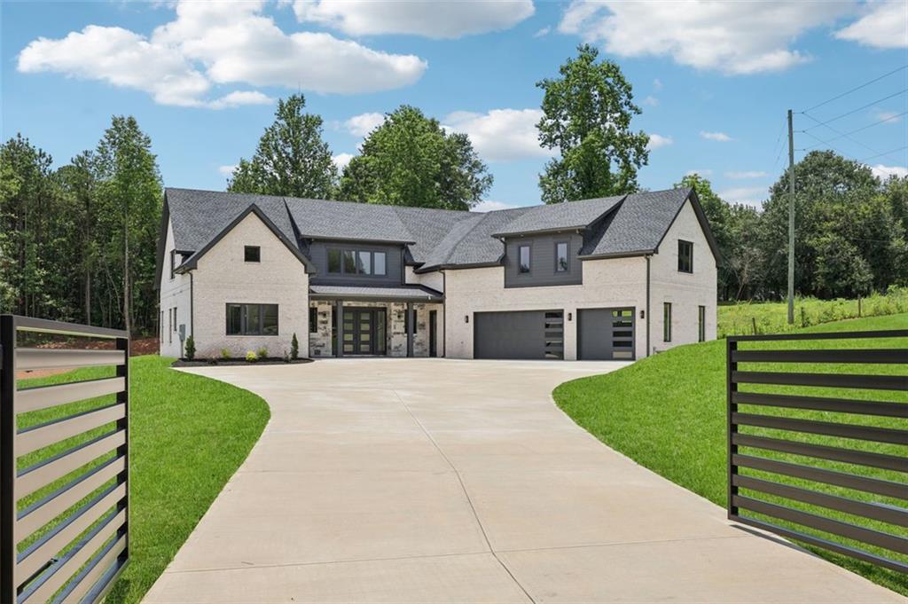 Welcome to this custom-built modern estate offering 5,053 square feet of luxury living on 1.19 private acres in Braselton, GA. With no HOA and a gated driveway, this 4-bedroom, 4.5-bath home blends modern design, smart home technology, and exceptional privacy. Inside, you'll find soaring ceilings, wide-plank hardwood flooring, and oversized European windows that flood the home with natural light while delivering superior efficiency. Foam insulation has been installed throughout the home, providing enhanced comfort and energy savings year-round. The open-concept living area features a custom fireplace with floating wood shelves and a modern tray ceiling with LED accent lighting. The home is equipped with smart home features throughout, offering enhanced convenience, comfort, and security. The chef's kitchen includes an oversized waterfall quartz island, custom two-tone cabinetry, premium gas cooktop, double ovens, full-height designer backsplash, and a hidden walk-in pantry. The spacious primary suite features vaulted ceilings with wood accents, a feature wall, and a spa-like bath with an oversized walk-in shower, freestanding soaking tub, dual vanities, and designer tilework. Additional highlights include a large mudroom with custom built-ins, a well-equipped laundry room with extra cabinetry, a spacious bonus room with wet bar and built-in shelving, and multiple flex spaces for work, entertainment, or fitness. The oversized 3-car garage features modern glass-panel doors, while the expansive concrete driveway allows ample parking. The septic system is located on the side of the property, leaving plenty of room in the backyard to add a pool or outdoor living space. A gated entrance provides privacy, and the property enjoys peaceful views of a neighboring property with horses, all while remaining conveniently close to Braselton's shopping, dining, and commuter routes. This modern estate offers a perfect balance of privacy, freedom, technology, and sophisticated design.