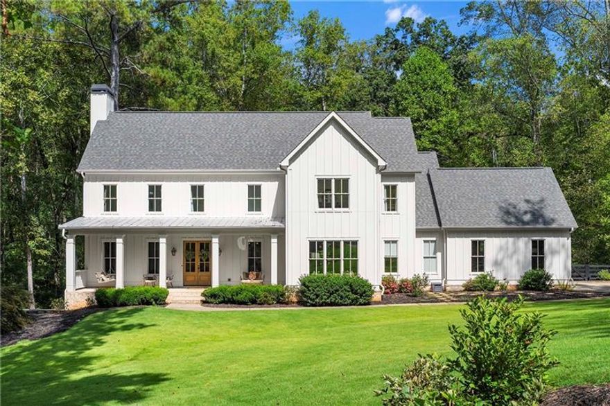 Tucked away on a private cul-de-sac in Long Shadows, one of Alpharetta's most picturesque equestrian enclaves, this modern farmhouse blends timeless architecture with modern comfort on 1.85  acres. A covered front porch with a metal roof and board-and-batten siding welcomes guests inside, where double doors open to an airy floor plan filled with natural light and thoughtful design.  The main level offers effortless living and entertaining. A fireside living room accented by a shiplap wall flows seamlessly off the foyer, as does the inviting dining room. The dark hardwood floors continue from the dining room into the chef's kitchen, which is appointed with double-stacked custom cabinetry, stainless steel appliances and an oversized island with seating. A walk-in pantry with built-in cabinetry and additional counterspace provides abundant storage, while a cozy sitting area just beyond the kitchen creates the perfect space for casual gatherings. Double French doors lead to a covered brick porch, ideal for grilling, dining al fresco or relaxing with views of the fenced backyard.  The primary suite is a private retreat with cathedral ceilings, abundant natural light and barn doors that reveal a spa-inspired bathroom. Here, marble-topped vanities, a clawfoot bathtub crowned by a crystal chandelier and a Carrara marble shower with a bench, product niche and a seamless glass door set a serene tone. An office and a convenient main-level laundry complete this floor.  The hardwood floors continue upstairs throughout a large landing-perfect for homework or movie nights. Three spacious bedrooms, each with an en suite bathroom, are joined by a generous playroom and a second laundry room with cabinetry, a sink and hanging space.  The finished terrace level extends the home's versatility with a very spacious recreation room, two additional bedrooms, a full bathroom and a gym.  Outdoor living is just as inviting, with a covered back porch featuring a dining area, television hookup, grilling area and a pavered patio with a hot tub overlooking the grassy play yard. The three-car garage and 1.85-acre lot offer both practicality and privacy.  Adding to the unique lifestyle of Long Shadows, Dreamland Farm at the end of the street offers horseback riding lessons and boarding, further enhancing the community's equestrian charm and appeal.  Located in Cherokee County with an Alpharetta address, this exceptional property enjoys the advantage of lower Cherokee taxes while being zoned to top-rated Avery Elementary and Creekview High Schools. This is a rare opportunity to enjoy refined farmhouse living with abundant space, enduring style and a coveted location close to downtown Canton, Woodstock, Roswell, Alpharetta, Crabapple Market and Avalon.