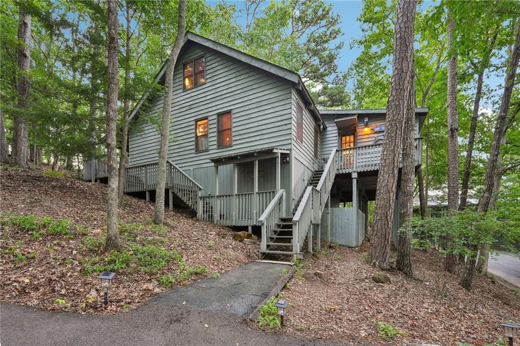 FULLY FURNISHED HOME! Just bring your toothbrush. Step into Big Canoe history with this one-of-a-kind 1978 Plummer Cabin, thoughtfully crafted by Dick Plummer himself and offered for sale with longtime artistic collector-owners antiques inside. Nestled in the heart of the Buckskull neighborhood, this original cabin blends rustic charm, artistic detail, and modern comfort—just steps from Lake Petit, with lake views from the side porch.From the moment you arrive, the elevated entry and wooded setting evoke classic mountain living. Inside, you’ll find a warm, inviting interior featuring natural wood finishes, vaulted ceilings with exposed beams, and a stunning floor-to-ceiling stacked-stone fireplace that anchors the great room. The spacious kitchen opens to a unique bar area (the original kitchen), perfect for entertaining, with seamless flow into dining and living spaces. Multiple sitting areas, both inside and out—including an unforgettable screened porch—invite conversation, cocktails, or quiet reflection. Sold fully furnished and brimming with carefully curated collectibles, antiquities, and truly one-of-a-kind finds, this home is more than just a mountain retreat—it’s a piece of Big Canoe’s living history. Whether you're searching for a personal getaway, a charming full-time residence, or an investment with rental appeal, this cabin checks all the boxes with style and soul. Roof replaced 3 years ago. The Buckskull neighborhood offers sewer, not septic. All appliances and furniture/ contents convey with the sale, making this charming mountain getaway move-in ready. Big Canoe is Atlanta’s premier mountain community, offering an unmatched lifestyle surrounded by 8,000 acres of lush national forest, with over one-third dedicated to wildlife areas and parks. Recognized by Georgia Audubon as a nature preserve, the community provides an array of extraordinary amenities, including golf, tennis, pickleball, bocce ball, a 13,000-square-foot Wellness Center, playgrounds, multiple dog parks, and 25 miles of scenic hiking trails. Residents enjoy the flexibility of membership options or pay-as-you-go access to these amenities. A mandatory $4,500.00 capital contribution fee paid by the purchaser to the Big Canoe Property Owners’ Association will be due at closing. Pursuant to Article II, Section 1, Paragraph bb of the Class “A” Covenants for the Big Canoe community, all property transfers are subject to the Big Canoe developer’s right of first refusal. Note that address is 44 Buckskull Brow. Some third party websites will list as "Buckskull Court."