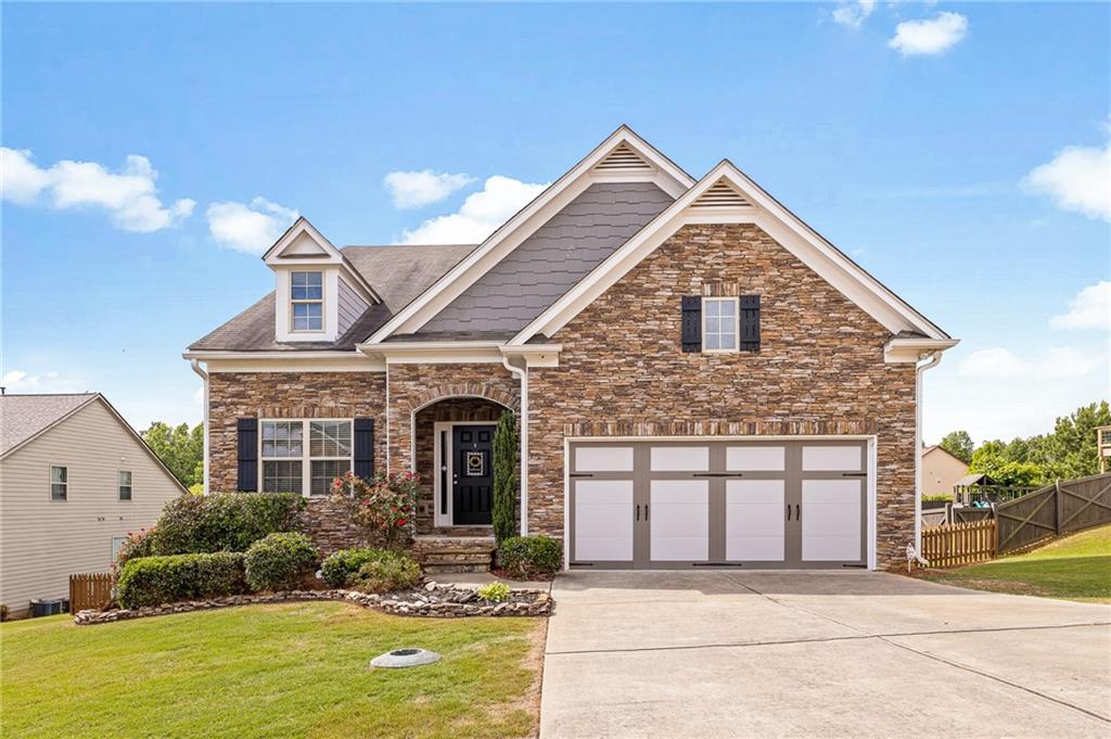 Welcome home to this beautifully maintained, two-story home located in Barrow County. This desirable 3 bedroom, 2 1/2 bathroom floor plan is situated on a large, flat, and fenced lot located in The Falls of Braselton subdivision. As you enter the home, you are welcomed by a bright and beautiful two-story foyer and dining room. The main level of this home boasts high ceilings, a large eat-in kitchen with a bar height island, beautiful engineered hardwood floors and stainless steel appliances. The open floor plan of the kitchen and family room makes a perfect space for entertaining guests. Off of the kitchen, you will find your laundry room, garage and entrance to the unfinished basement. Included on the main level, you will find a half bath and your oversized master suite with a generous walk-in closet and large master bathroom with his and hers dual vanities. As you head upstairs, you will find two secondary bedrooms, one full bathroom and a large loft area overlooking the family room below. This loft area offers endless media/play/workout possibilities. In addition to the 2,396 square feet of finished living space, the unfinished walkout basement boasts an extra 1,652 square feet of space to finish off depending on your needs - living area, extra bedrooms, office space, workshop, fitness room, extra storage, etc. The unfinished basement comes fully framed with electricity run throughout and is stubbed for a future bathroom. When it's time for you to relax, head out back to the large, fenced-in backyard, perfect for hosting barbecues or simply enjoying the fresh air and sounds of nature that come from the conservation area directly behind the home. The Falls of Braselton neighborhood features many wonderful amenities including a pool, clubhouse, fitness center, multiple tennis courts, playground and has its very own stop on the Braselton Trolley Route, where you can be picked up right at the clubhouse. If there isn't enough for you to already do within the community, enjoy an evening stroll or weekend adventure on the Mulberry RiverWalk trails or hop on your golf cart and take a ride on the oversized sidewalks to enjoy what route 211 has to offer! Conveniently located minutes from retail shopping, restaurants, Chateau Elan Winery & Resort and I-85, this home is waiting to be yours!