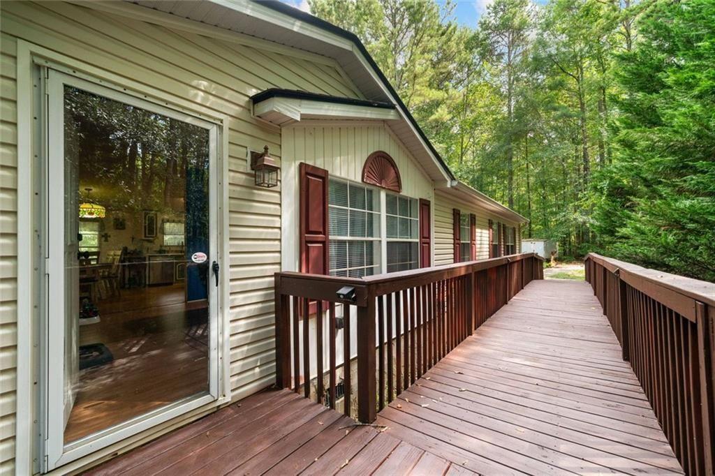 Peaceful country living on over 8 private, wooded acres with no HOA! This updated 3 bed, 2 bath ranch features new laminate wood flooring, fresh paint, and remodeled bathrooms. The kitchen boasts updated countertops, painted cabinets, dual backsplashes, new sink, and butcher block island. The oversized primary suite includes a versatile sitting area—perfect for an office, playroom, or bonus space. Enjoy upgraded lighting, ceiling fans, tankless water heater, large laundry room, and two storage sheds. Outside you’ll find a freshly painted deck, new front porch and stairs, and a wheelchair-accessible ramp. Tons of room to roam, garden, or expand—just minutes from downtown Monroe! **Landscaping shown in the primary photo has been digitally enhanced for illustrative purposes**