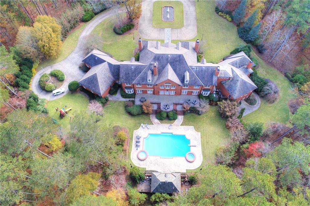 Within the esteemed enclave of North Valley and heart of Milton, lies a masterpiece of luxury estate living, sprawling across an impressive expanse of +/- 10 acres. This Georgian all-brick mansion, reminiscent of the Great Gatsby, is a monument to architectural finesse and unmatched refinement. Spanning more than 12,000 square feet, the estate presents an assemblage of magnificent living and entertaining spaces, crowned with 12-foot high ceilings, the highest quality of millwork and design, an illustrious slate roof, genuine copper gutters, and an elevator to gracefully ascend through its storied levels. Designed for the consummate host, the estate boasts a 54-foot swimming pool, complemented by two spas and a pool house with a kitchenette, setting the stage for gatherings of unmatched elegance and joy. At the heart of this splendid domain is a gourmet kitchen, a chef's dream, outfitted with triple islands, four dishwashers, four ovens, and a walk-in pantry, 2 fully equipped bar areas, poised to accommodate the most lavish of feasts and intimate gatherings alike. Inside guests are greeted by a dual staircase, a dome lighted ceiling, marble-tiled entryway, six fireplaces and an exquisite office space/cigar lounge, adorned with illuminated bookcases. Majestic living quarters, featuring a master suite on main, four grand bedrooms up, each with ensuite baths and walk-in closets, alongside a basement area exquisitely finished with a sauna, spa, and guest quarters. Outside you’ll find magnificently manicured grounds that promise solitude and a picturesque setting for outdoor entertaining. Within a locale that marries the tranquility of rural grandeur with the convenience of proximity to Milton and Alpharetta’s plethora of amenities, this estate also features a four-car garage and ample additional parking, emphasizing the utmost in construction quality with a lens focused firmly on luxury and seclusion. This estate stands as an invitation to those of discerning taste, seeking a residence that not only promises, but delivers an unparalleled lifestyle of elegance and exclusivity.