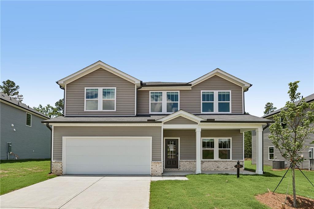 View of front facade with stone siding, concrete driveway, and a front yard