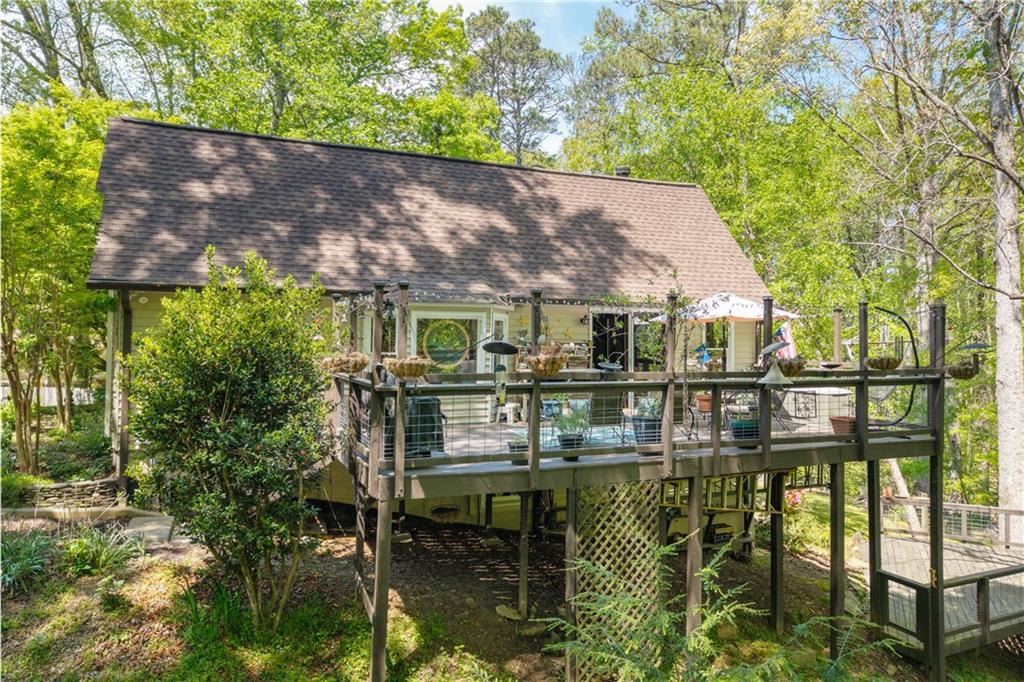 This perfectly maintained and incredibly charming cottage, tucked away from the road in a quiet neighborhood with NO HOA, is a nature-lover's dream, yet just minutes from everything the quaint and trendy town of Canton, Georgia has to offer! This one is truly move-in-ready and even has an income-producing downstairs apartment that is accessible to all, and comes with an established rental history too! The main bedroom is on the main level, as well as the laundry and one-level living (upstairs) comes complete with a sunny custom gourmet kitchen, newly expanded multi-level decks, updated and remodeled custom baths (with walk-in shower AND a soaking tub), and an established native garden that is like a little slice of pristine paradise! Relax on one of the expansive decks or beside the circulating wood stove in the cozy living room. Enjoy preparing meals on a gas cooktop in this chef's kitchen with a lovely woodland view from the breakfast nook, looking out of newly replaced custom kitchen windows with tons of clever cabinet storage. Bring your guests or loved ones to the downstairs apartment with its own separate entrance and a 2-car garage or the private terrace level deck that is all easily accessible. Host a garden party with a bonfire outback or take a hike to the river along the (seasonal) creek, all the way to the river! It doesn't get much better than this, private and quiet yet convenient too! Call or text today for an easy showing!