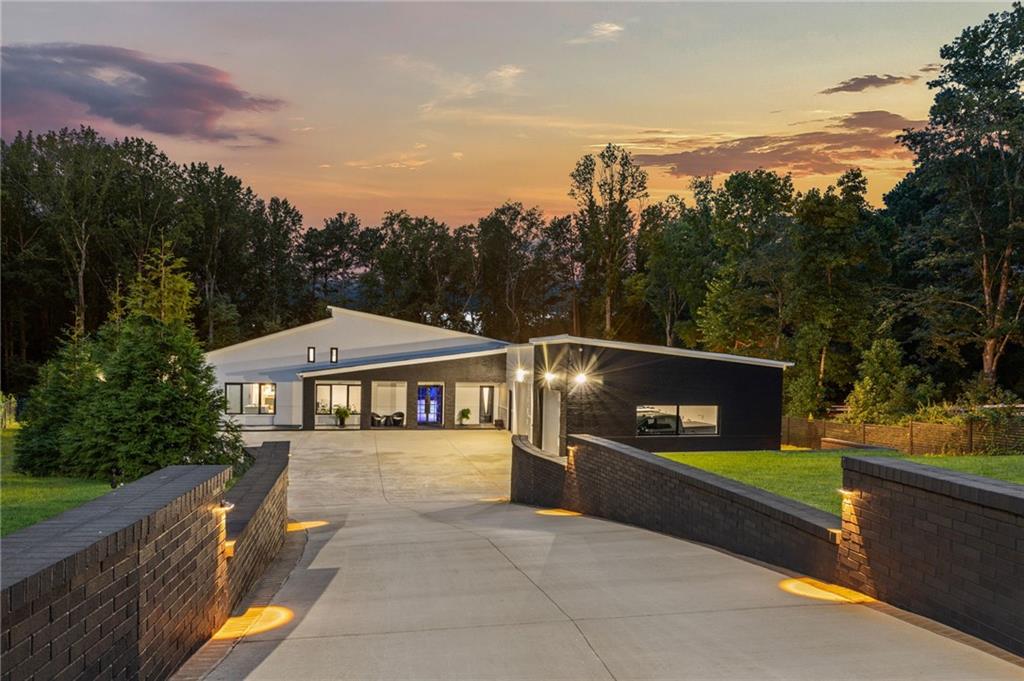 Pure Luxury in the Heart of Suwanee! Amazing Custom Craftsmanship, Curated Finishes Throughout, Modern yet Timeless, Elegant yet So Livable! This exquisite Contemporary European brick home is truly one of a kind, built with attention to every detail to achieve the level of quality, luxury, and livability that will provide a magnificent home for many years to come! Enter through the private gate leading to the beautifully landscaped 1.45 acre lot and proceed to the courtyard entrance with welcoming covered porch flanked by three heated and cooled garages with Tesla energy stations, including the extended garage with a sink and shower/pet-wash. The grand entrance welcomes family and guests with soaring ceilings accentuating the custom wood flooring, slat wood paneled walls, designer lighting and fixtures, and beamed ceilings. Well-equipped office space overlooks the courtyard and includes built-ins and adjacent bathroom. The huge great room features a lovely electric fireplace and separate open-concept dining room overlooking the pool. The kitchen is a masterpiece, featuring a huge stone island with space galore for prep and entertaining simultaneously. Sleek and modern, yet superbly equipped with built-in induction cooktop, microwave drawer, wall oven, wine refrigerator, double faucets over the oversized stainless farmhouse sink, and handy coffee bar. Custom laminate wall panels open to reveal two refrigerators and the huge custom pantry – Double-sided with dual function sliding shelves. The Primary Suite is the epitome of indulgence, extending along the length of the left side of the home and featuring custom wall coverings and lighting, built-in safe, and private access to the pool. The primary bath is truly a spa experience, with extended dual vanities, towel warmer, stand-alone soaking tub, double walk-in rain head shower, and sensor illuminated mirrors. The primary closet space is fabulous, with connecting spaces including built-ins, wardrobe cabinetry, extending up a private staircase to the off-season wardrobe closet. Outside, the portico invites relaxation and ease of entertaining with a view to the heated pool surrounded with plenty of decking and casual outdoor dining space. The outdoor built-in grilling station is conveniently located at the covered patio next to the pool. Adjacent to the pool is the guest apartment which can function as a secondary dwelling, pool house, or multi-generational living with its own detached garage, private entrance, bedroom, bathroom, kitchen, pantry, dining room, and laundry! This Smart Home features a surround system throughout, intercom for each room and at the entrance gate, and internet date controls via WIFI for the security system, thermostats, HVAC, cameras, and sprinkler system. The premium features of this home are too numerous to name, from the way the home was constructed, the materials used, and the upgrades that will make life so much easier and reduce maintenance needs. Some of the major enhancements include WeatherShield termite resistant framing with lifetime warranty, triple pane windows, whole house water filtration, Trane HVAC system, and hot water in 15 seconds! With a perfect location six minutes from the vibrant Suwanee Town Center, excellent North Gwinnett schools, no HOA, and easy access to I-85, this property is a once in a lifetime opportunity! Private tours can be arranged with the listing agent.