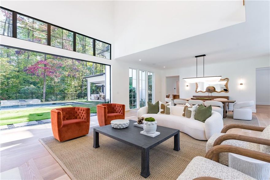 BRAND NEW home on a hilltop corner lot that spans 1.897 acres surrounded by mature trees and nestled among other beautiful estates on prestigious Davis Drive. The builder is including a $200,000 credit for the buyer to finish the basement.
The home faces west, providing an abundance of light through the vast walls of windows throughout the large open living spaces and lofty 12' ceilings. The floorplan and finishes are designed for those with a more modern design style, with open spacious rooms that feature natural hardwood floors, modern lighting, expansive windows, full accordion sliding doors and high ceilings that rise to at least 12 feet. Floor-to-ceiling windows also frame the main staircase allowing even more natural light to flow through the modern open tread design through to the great room.  A very desirable main level walkout pool, spa and lawn adjoin the great room, family room and primary bedroom, while an outdoor covered pavilion complete with a kitchen and fireplace enhance the outdoor living experience. The property also includes TWO 2-car garages and an oversized motor court. 

The generously sized kitchen is open to the breakfast room and family room and has sunny views of the pool and landscape.  Ceiling-height cabinets, a center island topped with a waterfall stone counter, a second prep island, and Professional Sub Zero and Wolf appliances are complemented by ample storage. Also adjacent to the kitchen is the friend's entry with a pool powder room, a mudroom and large laundry room. An elevator shaft provides access to all three levels.

The main level primary suite features an extra high ceiling, 2 separate vanities, a cosmetic vanity and oversized his & hers dressing rooms. Upstairs are 4 bedroom suites. 3 plus a living room, and the 4th completely separated down the hallway, and 2nd laundry room.  The unfinished 2000 sq ft terrace level is massive and occupies the entire footprint of the house - plenty of space for an open recreation area, bar, bedroom, full bath, media room, gym, wine cellar, and more. A $200,000 allowance is included in the price to finish it based on your preferred lifestyle needs.  The location is a short drive to private and public schools, excellent restaurants and shopping in Buckhead, and Chastain Park is just a few miles away. The top-notch team behind this project includes custom builder Deane Johnson, Libi Homes, Harrison Design architects, Neptune pools, and Land Plus for landscape architecture.  This beautiful new home is ready for move in now!