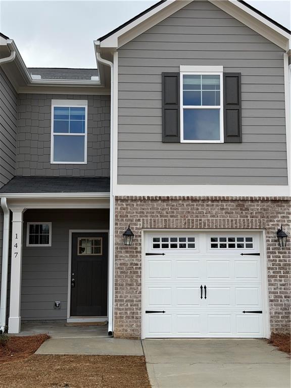View of front of home featuring a porch, brick siding, an attached garage, and concrete driveway