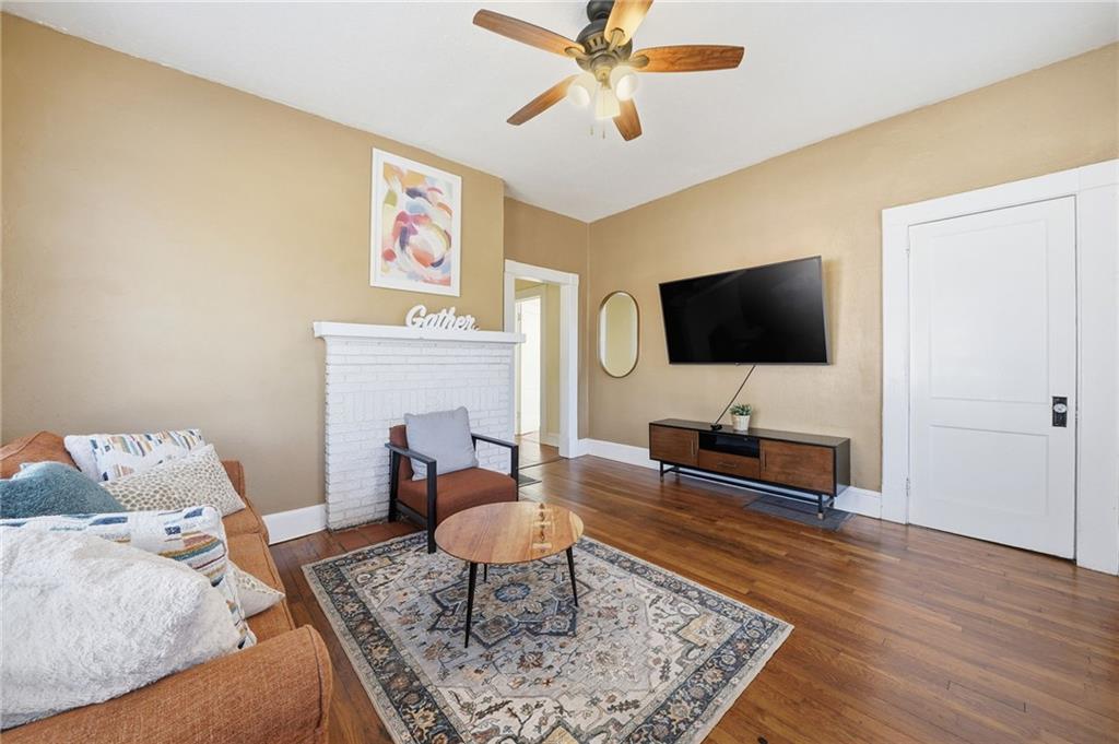 Cozy living room featuring a brown sofa with colorful throw pillows, a round wooden coffee table, a decorative area rug, and a mounted TV, highlighting a welcoming atmosphere in the duplex at 1420 Sylvan Road SW, Atlanta.