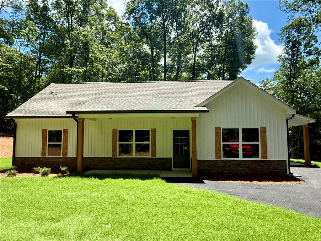 NEW CONSTRUCTION RANCH ON 3 QUIET ACRES – NO SUBDIVISION OR HOA!!! Act now for a FREE appraisal and $3,000 in incentives with our preferred lender. Conditions apply. See listing agent for details.
This stepless ranch home is under construction on a serene 3.098-acre lot -- offering the perfect blend of privacy and convenience. Conveniently located north of Buchanan off of Hwy 27 going towards Cedartown. Featuring 3 bedrooms and 2 full bathrooms, the home showcases an open layout with vaulted ceilings in the main living and dining areas for a spacious, airy feel.
There's still time for buyers to add their own personal touches! Contact the listing agent today! The kitchen is designed with granite countertops, a counter-height bar, and a stainless steel appliance package including an electric range, built-in microwave, and dishwasher. The split-bedroom layout provides privacy, and the primary suite features a walk-in closet and a bathroom with double vanities, framed mirrors, granite countertops, and a stand-up shower.
The two secondary bedrooms are generously sized and share a full bathroom with a granite vanity and a tub/shower combo. Ceiling fans are included in the living room and primary bedroom. Outside, the home will be finished in low-maintenance vinyl siding with a stone water table for added curb appeal.
This floor plan includes an attached carport. Tract 2 is also available and being marketed without the carport in another listing.
Don’t miss this opportunity to customize your dream home in a peaceful country setting! ***Photos are of a home similar to the one being constructed, not of the actual subject property.***Please note that the property is in the VERY EARLY stages of construction/clearing.***