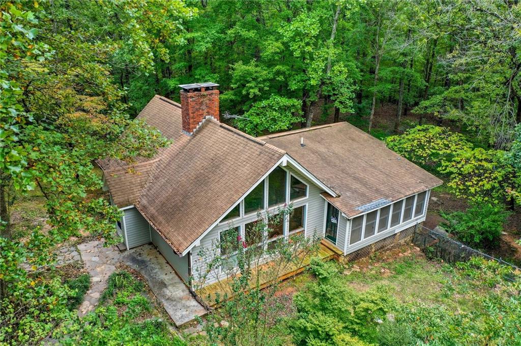 Tucked away on a private, wooded lot, this fixer-upper sits on nearly 5 acres and offers endless potential. Inside, the family room features beamed, vaulted ceilings, a dramatic stone fireplace with raised hearth, and large picture windows framing serene wooded views. The main level offers two bedrooms, including a primary suite with his-and-her closets and a large sunroom retreat, plus a full bath for convenience and flexibility. A separate dining room is perfect for gatherings. Upstairs, a spacious loft overlooks the living area and is ideal for a home office, studio, or playroom. The finished basement includes a full bath, with plenty of space for a second living area, home gym, or teen/in-law suite. Outside, the fenced yard offers a secure area for pets or gardening, with wooded acreage to explore, expand, or simply enjoy the peace and privacy. Located in the foothills of the North Georgia mountains, Jasper is known as the “First Mountain City.” Residents enjoy small-town charm with local shops, restaurants, and a historic downtown, plus quick access to outdoor adventures at places like Amicalola Falls, Gibbs Gardens, and the Appalachian Trail. Jasper is also a growing community with convenient access to Highway 515 for an easy drive to Atlanta. Bring your vision and make this property your own. It’s an incredible opportunity in the heart of Pickens County.