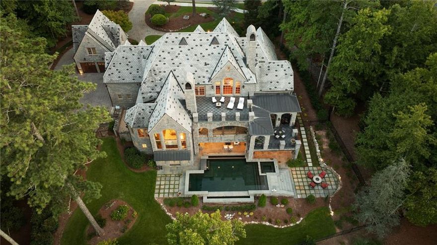 “The Castle” at The River Club"
Welcome to The Castle, an extraordinary full-limestone Italian estate where timeless architecture and modern luxury converge. Built with craftsmanship seldom found today, every detail speaks of artistry and purpose—from the rich heart Rocky Mountain pine flooring to the custom, chosen for both beauty and lasting quality. Privately situated in one of The River Club’s premier locations, the property captures panoramic views of the 8th hole and shimmering lake. These vistas surround the home, visible from the fireside keeping room, covered outdoor terraces, and the showstopping double infinity-edge pool where water meets horizon. The main floor offers elegant formality and comfortable warmth. The fireside great room, formal dining room, and leather-paneled study exude refinement, while the gourmet kitchen with stone fireplace keeping room invites casual gathering. A breakfast room, artistic two-way walk-in pantry, and guest suite with a steam shower bath complete this level. Upstairs, the owner’s suite is a truly Italian-style masterpiece—a sanctuary with a fireplace, coffee bar, private terrace, and intimate loft accessed by its own spiral staircase. The spa bath is crowned by a hand-painted domed ceiling with cherubs, a crystal chandelier above a black soaking tub, floor-to-ceiling stone, heated floors, steam shower, and dual private water closets. The expansive walk-in closet recalls a bespoke European atelier, complete with hidden cedar closet and dressing mirrors. Three additional bedrooms each have distinct personalities: a luxurious cabin retreat with mural, hardwood planks, and metal ceiling; a princess suite in soft purples with hand-painted art; and a sunlit sanctuary in serene tones. The indoor staircase to the terrace level is finished with plush carpet and a hardwood handrail, while outside, a graceful spiral staircase connects the upper terrace to the pool level. The terrace level is an entertainer’s haven—a full Irish pub, billiards room with brick flooring, media room with movie theater screen, home gym, steam/dry saunas, and space for a massage area. Another guest suite offers privacy, with decks leading to the pool and outdoor entertaining areas. The property features a two-car attached garage and a two-car detached garage. Above the detached garage, a private retreat awaits—ideal for a golf simulator, gaming, music studio, hobby space, or the ultimate man-cave. Both garages have carriage-style cedar doors and are joined by a paver driveway that adds timeless curb appeal. From coffee on the enclosed porch to starlit evenings on the terrace, The Castle is more than a home—it’s a lifestyle of elegance, craftsmanship, and enduring sophistication.