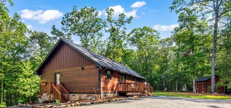 Welcome to 108 Red Hawk Trail - a meticulously maintained, custom-built one owner cabin nestled on 3 private acres in the heart of Ellijay. This charming 2 bed, 2 full bath one-level home offers serene mountain living with modern conveniences. Built just 7 years ago this cabin features a 2018 roof, HVAC, and hot water heater, plus a dual-fuel heating and air system, whole-house water filtration, and an electric monitor for efficient climate control. The kitchen boasts warm wood cabinetry, stainless steel appliances, gas stove, Formica countertops, and durable vinyl planking flooring. Enjoy the open dining area and cozy living room, complete with backup propane heat and space for a future fireplace. Thoughtful upgrades include brand new staining on all porches (front, side, and back), freshly painted trim. 36-inch doorways offering potential wheelchair accessibility. Washer and dryer are conveniently located on the main floor, with a brand-new washer and a separate mudroom entry. The closet near the living area could be easily converted into a bunk room. The spacious master suite includes a massive walk-in closet that could double as an office, and an ensuite bath with vinyl planking flooring, fiberglass surround tub, and linen closet. The guest bedroom and bath offer comfort and convenience with vinyl planking flooring and a fiberglass tub. Outside, you'll find beautiful stonework sourced from the property itself, newly added landscaping, a 330-gallon buried propane tank, and a seasonal mountain view. The 12x16 outbuilding is only 4 years old, ideal for storage, workshop, or hobby space. With a covered picnic area. There's also a firepit area, and ample flat parking. Vacation rentals are allowed, fiber optic internet is available, and the HOA is just $25 a month with a club house and field for playing with a creek! Whether you're seeking a full-time residence, mountain getaway, or short-term rental opportunity-this property checks every box! Conveniently close to hiking trails, fishing,and biking areas, many Apple Orchards and Wineries!