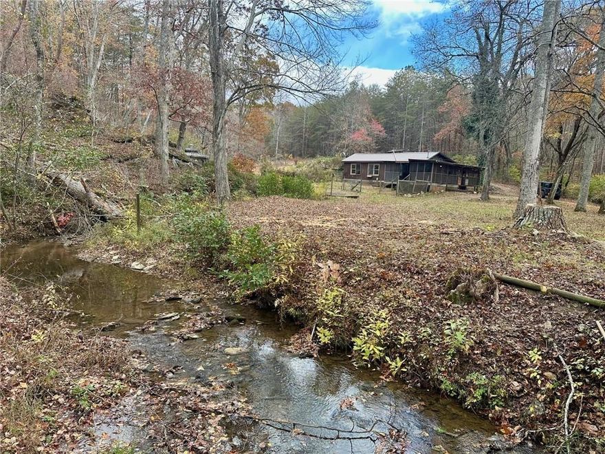 Over the river & through the woods to this absolute gem of an opportunity! A little slice of North Georgia heaven. 4-/+ acres with an adorable fixer cabin & two additional storage buildings. Three creeks converge here. One on either side of the property & a third joining in below the rock outcroppings. Towering hardwoods line the driveway & yard into the end-of-the-road privacy. Beautiful fenced fields roll gently behind this creek front homesite. The noise of the creek & visual ambience are king! Would make an excellent homestead or a wonderful, secluded vacation spot.
