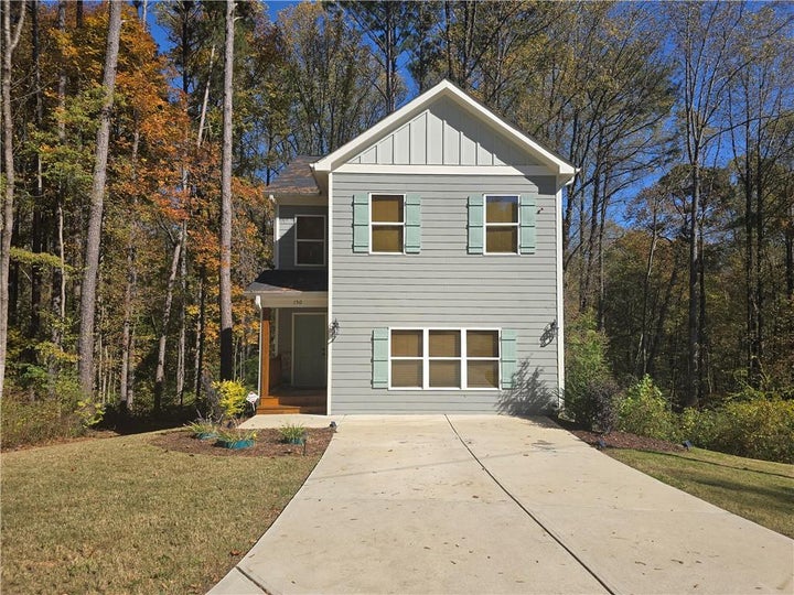 View of front of property featuring board and batten siding, a front lawn, and concrete driveway