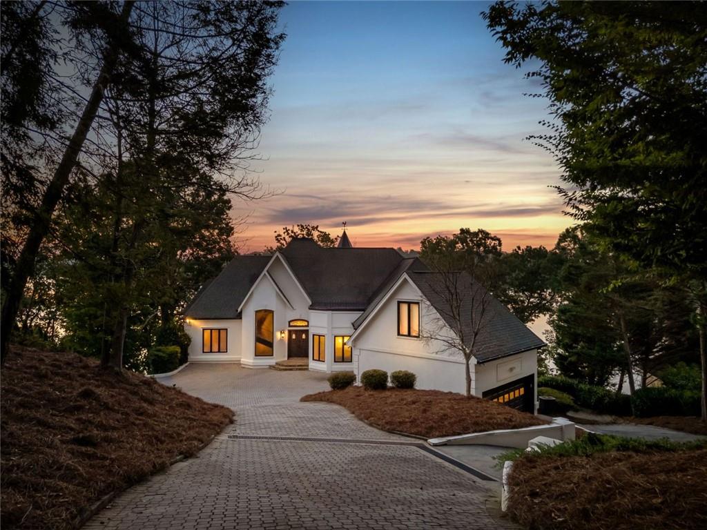 PRICED TO SELL!! Introducing The Chateau on Lanier - lakeside luxury living with this meticulously maintained estate on Lake Lanier. The estate's prime lakefront location includes a private DOUBLE-SLIP dock in DEEP water, which is just an easy stroll from the home. This residence is a truly exceptional, fully furnished 8-bedroom, 6.5-bathroom gated home and is perfectly positioned on 0.72 acres, offering breathtaking panoramic lake views from every level. Enter a world of elegance where stunning lake views are framed by multi-level balconies and expansive windows. The main level of this three-story estate features a chef's kitchen with commercial-grade stainless steel appliances, seamlessly flowing into the keeping room and dining area-all with captivating lake views. The family room opens to a balcony, making a perfect place to enjoy your morning coffee. The main level includes a massive mudroom with double washers and dryers, a sink, and a rear staircase leading to the terrace level. Two spacious guest bedrooms, one a secondary primary suite with their own private en suite bathroom, enhance the main level's appeal. Take the spiral staircase to the upper level, where the primary suite offers French doors, ample space, and panoramic lakefront views. This suite features a massive en suite bathroom with double vanities, a whirlpool tub, a grand tile walk-in shower, and a custom-built closet with an additional washer and dryer for added convenience. An additional secondary bedroom on this level also boasts an updated en suite bathroom. The terrace level is an entertainer's dream or the perfect in-law suite, complete with a full kitchen, bar, and living room. This level also includes three guest bedrooms and two full bathrooms, plus a spacious bunkroom ideal for a media room or recreational space that could be easily converted back to an additional two car garage with tons of storage. Enjoy year-round swimming in the heated pool. Perfectly located just off Dawsonville Highway, this estate is minutes away from dining, shopping, and more, offering the ultimate blend of serene lakefront living and modern convenience. Don't miss the opportunity to own this exceptional lakeside retreat.