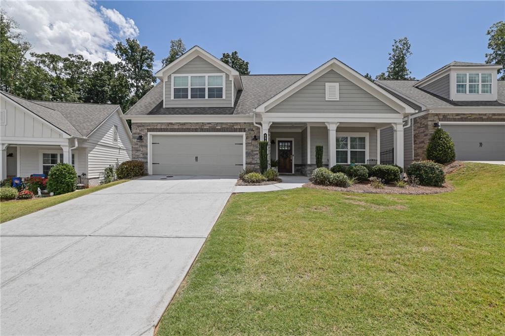 Welcome to effortless living in one of West Cobb’s most desirable 55+ communities—The Courtyards at Camden. This impeccably cared-for home blends smart design with luxurious upgrades, offering a relaxed and low-maintenance lifestyle just minutes from Mars Hill, Stilesboro, Brookstone, and the Northwest YMCA.
Inside, the spacious Promenade floor plan by Traton Homes showcases open-concept living with abundant natural light and elegant finishes throughout. Step from the charming front porch into a welcoming foyer that opens to a private guest bedroom and full bath—perfect for visitors or a quiet retreat. The heart of the home is the expansive great room featuring a cozy stone fireplace with built in cabinets, a dining area, and a chef-inspired kitchen outfitted with beautiful cabinetry, custom lighting, pull-out drawers, and a large pantry. Just off the kitchen, a versatile room with French doors is ideal for a home office. Adjacent to the kitchen and garage, is a large custom walk-in laundry room with built-in cabinetry and a laundry sink. The hall closet featuring a closet system adds valuable space for hobbies, seasonal items, or pantry overflow. Outside on the private side courtyard and you’ll find an incredible outdoor living space designed for outdoor entertainment. Retreat to the expanded primary suite with ample space for a sitting area or reading nook, plus a spa-like en suite bathroom complete with a double vanity, a step less walk-in shower. A massive walk-in closet and stylish window treatments add to the comfort and appeal. With neutral tones, luxury vinyl plank flooring in the main living areas, plush carpet in the bedrooms, and thoughtful storage throughout, this home is move-in ready. Low monthly HOA dues of $270 include lawn care, termite bond, trash service, and full access to the community clubhouse, fitness center, pool, and dog park. Plus, Cobb County offers a fantastic school tax exemption for homeowners 62+—a major bonus!