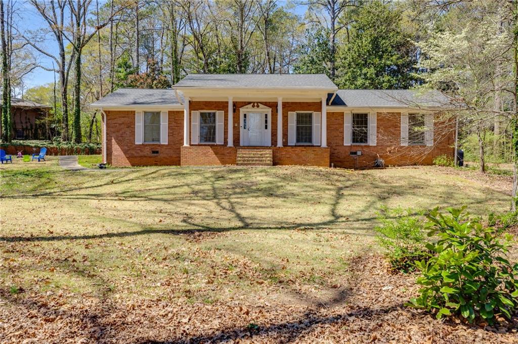 LET'S SAY WELCOME HOME! An all-brick ranch home offers timeless charm and unbeatable convenience! Perfectly situated on a private, one-acre lot within walking distance to downtown Douglasville, this well-loved home boasts 3 bedrooms, 2.5 baths, and 2,762 square feet all on ONE LEVEL! Step inside to a welcoming foyer that wows with a full wall of custom cabinetry for all your storage needs and built-in bookshelves that elegantly separate the foyer from the oversized living room. The open-concept flow continues into a huge dining room featuring a large pantry closet, perfect for hosting gatherings. The kitchen exudes a delightful retro charm with abundant cabinetry, an oversized island/bar for entertaining, and seamless connectivity to the spacious family room, complete with a cozy brick fireplace and additional built-ins. Retreat to the expansive owners suite, offering an impressive four closets and an ensuite bath. Two generously sized secondary bedrooms share a Jack-and-Jill bath, each featuring ample closet space. A wide hallway lined with additional storage, a separate laundry room, and a convenient kitchen-level entry from the carport add to the home's functional appeal. The property also includes a partially finished crawl space with a concrete floor, ideal for a workshop, plus an outbuilding in the backyard for additional storage. Enjoy peaceful evenings grilling on the back patio or customizing the private, wooded lot to fit your outdoor vision. Don't miss this opportunity to own a well-built home with incredible potential in a prime locationCojust minutes from I-20, restaurants, shopping, and the hospital!