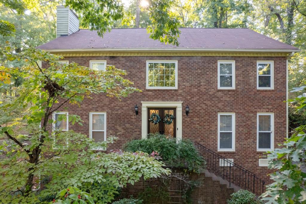 Welcome to this classic and beautifully updated brick home located in the highly sought-after swim and tennis community of Lansdowne. This beautiful property offers a perfect blend of modern updates and timeless charm, ideal for comfortable living and entertaining. Upon entering, you are greeted by a welcoming foyer that opens to a bright living room featuring double French doors and an elegant dining room. The spacious family room boasts a cozy fireplace, creating a warm and inviting atmosphere. The adjacent kitchen is a chef's delight, featuring white cabinetry, stone countertops with a stylish tile backsplash, and stainless steel appliances including a gas range. A convenient computer nook/desk and a sunlit breakfast area complete this functional space. The kitchen opens to a charming sunroom, providing seamless access to the outdoors. Step outside to enjoy the expansive deck, complete with a swim spa lap pool/hot tub and patio area, overlooking the private wooded backyard perfect for outdoor gatherings and relaxation.The upper level features an oversized owner's suite with a tray ceiling and a luxurious updated bath. The ensuite includes a vaulted ceiling with a skylight, a double vanity, a separate shower, and a freestanding soaking tub. A large custom walk-in closet provides ample storage. Three additional secondary bedrooms share a well-appointed hall bath. The laundry room rounds out the upper level. The finished terrace level offers exceptional versatility, featuring a kitchen, bedroom, full bath, a second laundry area, and a separate entrance ideal for an in-law suite or guest accommodations. Located in a vibrant neighborhood with outstanding amenities including a clubhouse, pool, tennis courts, and a serene lake, this home is perfectly situated near shopping, dining, parks, and major highways (I-75 and I-575). It is also within the highly acclaimed East Cobb School District, offering top-rated educational opportunities. Don't miss the opportunity to make this exceptional home yours!
