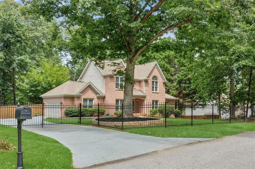 No HOA /.60 Acres /Upgraded Kitchen/ Fenced Yard/ Prime Flowery Branch Location
Welcome to this beautifully maintained and landscaped 4 BR, 3.5 BA home in the heart of Flowery Branch-offering nearly 2900 sq. ft. of living space on a generous .60-acre lot. Timeless and exceptionally well built, this home combines classic design with modern upgrades, making it both inviting and enduring in quality. This home offers extra security with a state of the art security system, cameras, iron fence in front with an iron gate at driveway ready for an electric opener as well as a privacy fence fully enclosing the back yard for added peace of mind. The main level offers a large second Master bedroom/owner's suite featuring new hardwood floors, private bathroom and spacious walk in closet. Inside you will find a flexible layout featuring a separate dining room and a versatile sitting room/living room/office space/music room. Beautiful upgraded kitchen, outfitted with brand new stainless steel appliances-including refrigerator, dish washer, gas stove top and a high end Kitchen Aid double oven. Granite countertops, freshly painted Nantucket-inspired cabinets and brushed gold hardware and faucet add a luxurious touch. The kitchen opens seamlessly to the family room where vaulted ceilings and a gas-log fireplace create a warm, open gathering space. Laundry room tucked away in the hall. Upstairs, you'll find two bedrooms with a shared bath and a second spacious ensuite featuring vaulted ceilings, walk in closet, huge bathroom with upgraded with brushed gold fixtures, separate tub and shower, his and hers vanities. The next stop is the outside oasis with an expansive deck overlooking a private, wooded backyard complete with a fire pit. You will enjoy many family gatherings on this amazing deck, the possibilities are limitless. This community is unique with more than 10 entrances to Lake Lanier, 4 minutes from the Famous Antebellum restaurant in the Historic Downtown Flowery Branch, 6 minutes from lake side dining at Fish Tales, 7 minutes from shopping at Stonebridge Village, 17 minutes from Lanier Christian Academy and 20 minutes to NEGA Medical Center in Braselton.