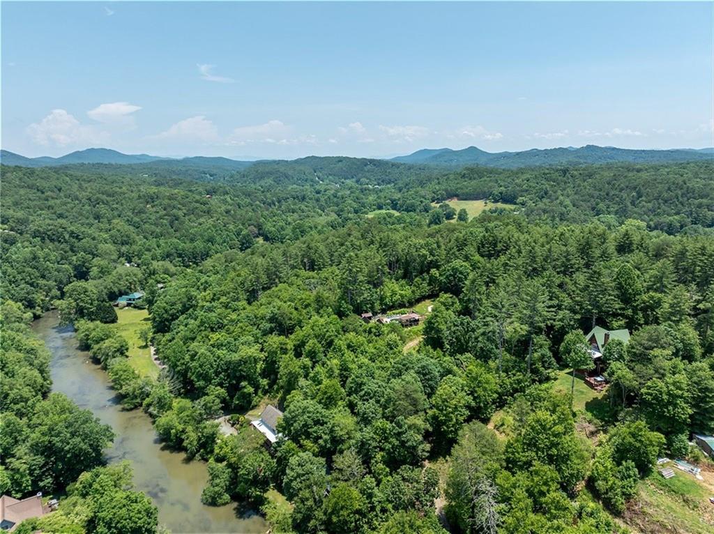 Unlimited potential to grow a business, develop, or enjoy as a secluded family retreat — 13.2+- acres in Blue Ridge with RARE Toccoa River frontage and access (the largest on the market), AND mountain terrain, trails and views. Currently operated as Toccoa House Properties for cabin rentals and special events, with four cabins, an event space, community swimming pool, regulation pickleball court, four cornhole courts, a nine-goal disc golf course, horseshoe pit, and playset, plus priceless natural amenities including hiking trails and fishing access. The property feels secluded and remote but is close to downtown Blue Ridge, which has become a hot real estate market and destination for shopping, dining, craft breweries, and entertainment. The property feels secluded and remote but is close to downtown Blue Ridge, which has become a hot real estate market and destination for shopping, dining, craft breweries, and entertainment — and a quick drive to popular Old Toccoa Farm semi-private golf club. Relying solely on word-of-mouth marketing, the rental business has been successful, and is primed for the next operator or developer, with mostly untapped potential to become the epitome of Blue Ridge destinations. Schedule a call and tour to discuss developing the riverfront, increasing river accessibility for fishing and paddle launch, upgrading vehicular access for existing walking trails. The existing cabins are currently in the rental program, and could continue to be used as-is or polished up for higher rates. Don’t miss the opportunity for a rare piece of land in the mountains, with Toccoa River frontage, and untapped potential for a business, development, or family retreat.