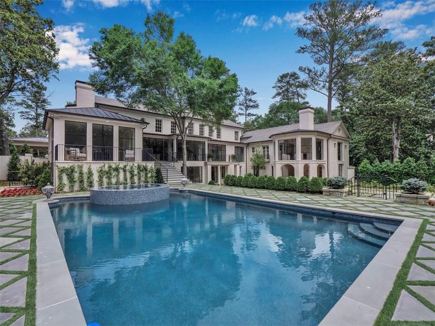 Introducing a grand Buckhead classic, brilliantly reimagined by Buckhead Development and Tish Mills Interiors. With an eye toward honoring its history and stateliness, the design-build team fused architectural pedigree with modernization to effectively create a home that lives like brand new. Built in 1955, this fabulous estate is happy and bright, shining more beautifully than ever. Every detail reflects a masterful renovation, starting with the original front door, restored and fitted with replated decorative knobs. Inside, natural light plays a starring role—spaces have been opened dramatically, with new massive walls of steel windows and doors washing the interiors with sunlight. Removal of walls now allows the curves of the foyer’s staircase to make an elegant statement, leading the eye up to the striking leaded-glass skylight. Reclaimed wide-plank white oak flooring spans the main level, with a contemporary mitered chevron pattern in the foyer to set a tone of refined craftsmanship. Simplified moldings and chic trimwork offer a lighter, more modern aesthetic, while the six gas fireplaces received sleek mantle upgrades. The formal dining room now opens to its own courtyard and kitchen garden, and the main level study is both sophisticated and comfortable. The kitchen is a masterpiece by Design Galleria, centered around a “Peacock Blue” La Cornue “CornuFe Series” range beneath a custom hood. Enjoy beauty and function with marble countertops, Baldwin hardware, Miele refrigerator/freezer, wine storage, and adjacent scullery with two additional ovens, ice maker, and prep sink. The main floor is ideal for hosting on a grand scale, with a spacious keeping room and breakfast area, plus new steps from the kitchen leading directly to the pool. The accordion-style steel doors open to a balcony overlooking the garden and pool, a perfect spot to set a bar for a party. The primary suite on the main level is a dream for two—enter from a dramatic vestibule, and immediately notice the new barrel-vaulted ceiling. Dual bathrooms and closets are on either side of the hall, both exquisitely outfitted to rival any spa—in one, find an antique mirrored wall and one-of-a-kind tub sourced from Europe and carved from a single block of marble (the only piece of art you need in that space!). Both are all marble, featuring mosaic marble “rugs” and spacious showers. Within the primary suite, find a cozy sitting room with fireplace, and a sun-drenched conservatory-style space with motorized shades and dynamic views of the pool and lush grounds. Upstairs, all bedrooms feature smartly reconfigured closets and marble en-suite baths, and the gracefully opened hallway leads to a main laundry room with double washer and dryer. The terrace level offers every amenity: a private guest suite with fireplace and outdoor access, morning bar, recreation room, wine cellar, and large gym finished with nickel gap paneling and gym flooring—all just steps from the pool and spa. The 1.72+- acre grounds of this home are quite spectacular. The English gardens are tailored, while a new, flat grass yard is the ultimate play space. The pool is surrounded by turf and bluestone pavers, and has been re-pebbled and redesigned with an updated spa. The gazebo has been transformed into an entertaining porch, also perfect for birdwatching. A new outdoor kitchen and restored fireplaces, plus new sophisticated landscaping touches throughout, create a uniquely tasteful and functional outdoor space. Beneath the beauty, the home is effectively new: spray foam insulation throughout, all new plumbing and electrical, tankless water heaters, new HVAC systems, and a modern alarm system. Parking is plentiful, with a brand new carport (easily enclosed, if preferred), a single-car garage with EV charger (near the guest suite for a private entrance), a two-car garage with an organized tool room, discreet service entrance via a cul-de-sac, and dedicated bike storage area.