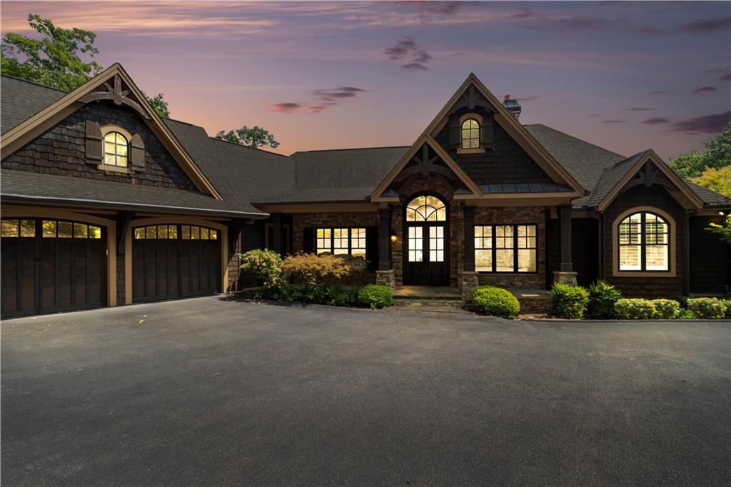 Luxurious Cox Mountain Retreat with Sweeping Panoramic Views is ready to be yours. Perched at the summit of Cox Mountain, this extraordinary 4-bedroom, 3.5-bath executive residence delivers awe-inspiring 180-degree vistas, from the shimmering lights of Atlanta to the rugged profile of Stone Mountain. Built in 2010 with exceptional craftsmanship, every detail of this custom home reflects timeless mountain elegance. From the moment you arrive, the home’s commanding presence draws you in, rich cedar shake siding, stone accents, arched windows, and a welcoming front entry framed by lush landscaping and soft evening lighting. With timeless craftsmanship, the residence showcases soaring cathedral ceilings with exposed beams, 8-foot solid doors, custom millwork, and designer finishes throughout. The open-concept great room centers around a dramatic floor-to-ceiling stacked stone fireplace, while the gourmet kitchen impresses with premium appliances, custom cabinetry, a spacious island, and breakfast bar, ideal for both everyday living and entertaining. A separate living room, three stacked stone fireplaces, a full wet bar, built-in safe, and billiard table offer endless spaces for gathering. Hardwood floors grace both the main and terrace levels. Additional thoughtful touches include a screened-in porch for year-round enjoyment, multiple expansive decks designed to capture the panoramic views, and a professionally landscaped driveway edged with a stacked stone wall and integrated lighting. Outdoors, relax in the jacuzzi hot tub under a canopy of stars or enjoy the private dog run. Perfectly positioned just minutes from the Post Office, Clubhouse, and main gate, this home combines privacy with convenience to all of Big Canoe’s premier amenities. A rare opportunity to own one of the community’s finest homes—schedule your private tour today!
