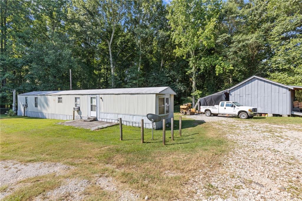 Now eligible for cash, conventional/FHA/VA financing. This mobile home, situated on a level and fully fenced 0.63-acre lot, presents a fantastic opportunity for a small family residence, roommate rental setup, or investment property—whether for rental income or future land development. The home features an open-concept floor plan combining the living room, dining area, and kitchen, creating a welcoming and functional living space. On one side, you’ll find a spacious bedroom with an en-suite bathroom, while the opposite end of the home boasts an even larger master-style suite, offering privacy and comfort. All major appliances, including the washer and dryer, are included with the sale. The property also features a separate outbuilding with two attached pole barns—ideal for additional storage or covered parking. Enjoy the benefits of a private well (no monthly water bill) and a recently serviced septic system, both in excellent working condition. The expansive front and back yards are fully fenced, making it perfect for pets or outdoor activities. This cozy and comfortable home is move-in ready, with plenty of potential to personalize or enhance further.