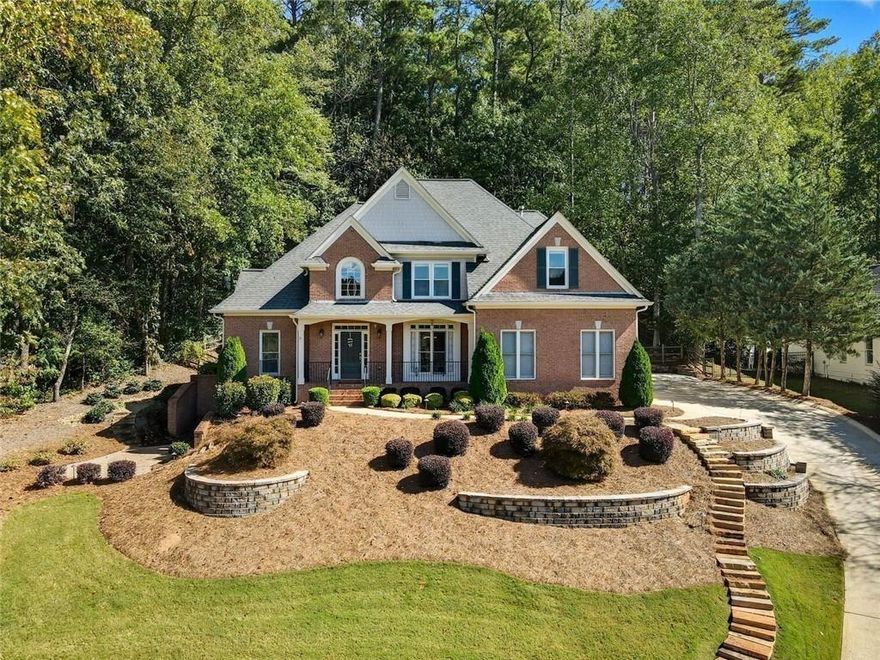 A Rare Find in Bradshaw Farm: Primary Suite on Main Plus Outdoor Living You'll Love

Set on a professionally landscaped lot in one of Woodstock’s most sought-after communities, this five-bedroom, four-bath home pairs timeless brick architecture with thoughtful upgrades inside and out. A wide front porch with brick steps and stately columns welcomes you home, while terraced stone walls and manicured landscaping enhance the curb appeal.

Inside, the main level offers both functionality and comfort with a spacious primary suite featuring a walk-in closet and an oversized bathroom with separate vanities, a soaking tub, and a walk-in shower. An additional bedroom and full bath on the main level offers flexible space for guests, aging-in-place needs, or a quiet home office.

The heart of the home, the two-story great room, boasts a wall of arched windows and a fireplace that draws the eye up to the soaring ceiling. The kitchen is open and bright, outfitted with white cabinetry, granite countertops, stainless steel appliances, and a breakfast bar overlooking the screened porch and deck.

Step from the kitchen into a vaulted screened-in porch with exposed beams, then out to a freshly stained deck with room to grill, dine, and unwind. The fenced backyard is tree-lined for privacy with space to garden or play.

Upstairs, you’ll find three generously sized bedrooms and dual entry bathroom. The finished terrace level extends your living space with multiple recreation areas, built-ins, a full bath, and a convenient kitchenette perfect for hosting, hobbies, or multigenerational living.

Enjoy all the perks of Bradshaw Farm living including golf, pools, tennis, pickleball, volleyball, clubhouse, and more just minutes from vibrant Downtown Woodstock, top-rated schools, and everyday conveniences.