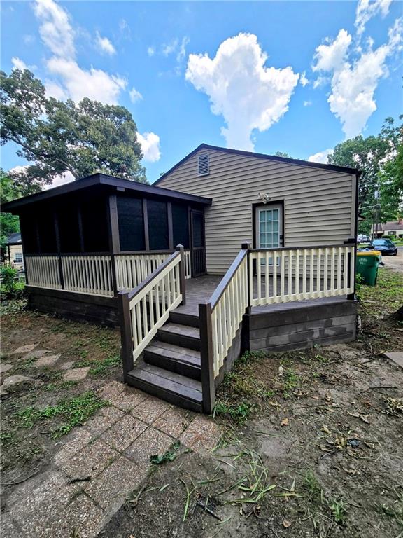 Multi-level wooden deck with painted railings, leading to a screened porch addition