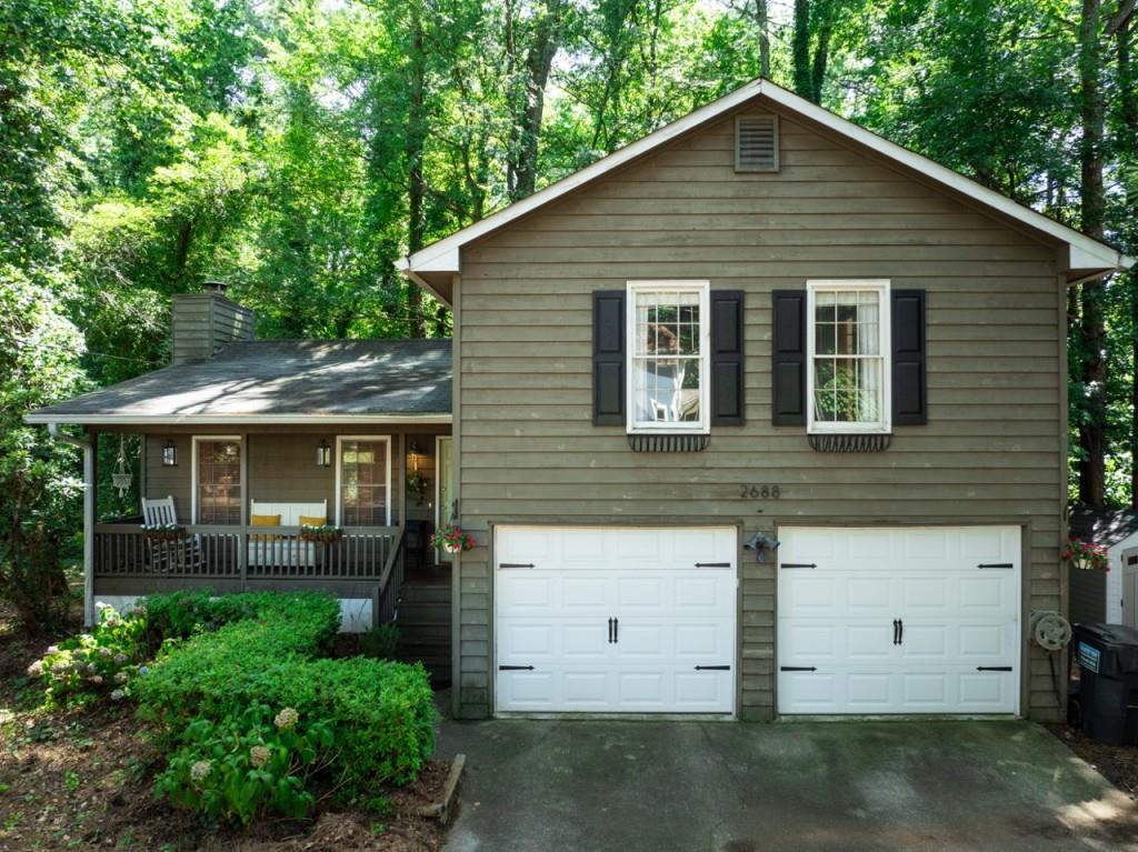 This is it! From front porch sitting to back deck living, this home has it all! The vaulted living room boasts a floor-to-ceiling stone fireplace, with beautiful original hardwoods. Natural light pours into this spacious living area, with fresh paint & modern light fixtures. The updated kitchen includes quartz countertops, solid-wood custom shelves, stainless steel appliances, a large, sparkling porcelain sink & an abundance of cabinet storage. Step out of the dining space onto a private, covered patio - with a brand new deck! Enjoy a serene, wooded retreat, as you sit beneath the tin roof and sip your coffee. Venture upstairs to find solid, white oak custom flooring in the hallway and all three bedrooms. Discover the oversized primary bedroom with two large closets, en suite with a bathtub, and bright windows that flood in the sunlight. Sit on the front porch and you'll soon see neighbors, constantly out walking in this quiet & peaceful community. Other features include a new HVAC system, an expansive 2-car garage complete with cabinets & shelving, and a storage shed on the side of the house. Located less than 10 minutes from both Downtown Duluth & Historic Norcross, a new adventure is always nearby! Nestled toward the middle of the neighborhood, this home feels tucked away, though just a few minutes from grocery stores, restaurants & more. Convenience, coziness, character & charm. This treasure of a property is move-in ready, only waiting for you... Welcome home!