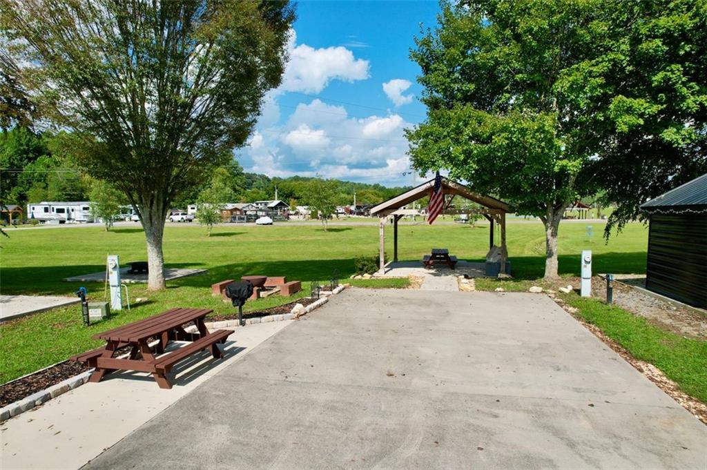 Welcome to your mountain getaway! This spacious RV lot has everything set up for comfort, convenience, and fun in the North Georgia mountains. Located in a desirable RV/tiny home community, it features a custom 18' x 18' pavilion with a custom-built Amish swing, power and additional outlets already added for more fans and lighting, string lights, a fan and space to fit a custom-built fireplace, giving you options to enhance the space further. The extra-large concrete pad (23' x 90') easily accommodates larger RVs, with a bump-out area perfect for a picnic table or extra seating.
The lot is level and shaded - one of the largest shaded lots in the community, creating a cool retreat during the warmer months. A small brook runs along the back, with the community disc golf course and green space just beyond, giving you a peaceful view without losing privacy.
For unforgettable outdoor gatherings, there’s a fire pit with four custom benches and a park grill - ideal for evenings spent making ever-lasting memories.
As part of the community, you’ll enjoy gated access and amenities including a pool, clubhouse, playground, dog park, basketball, trout creek, two catch-and- release ponds, and more - all just minutes from charming downtown Blue Ridge, Lake Blue Ridge, Toccoa River, orchards, wineries, waterfalls, and hiking trails.
This lot offers both flexibility and mountain charm and is great for a personal getaway or an investment with great rental potential. Great rental history, can provide it by request.