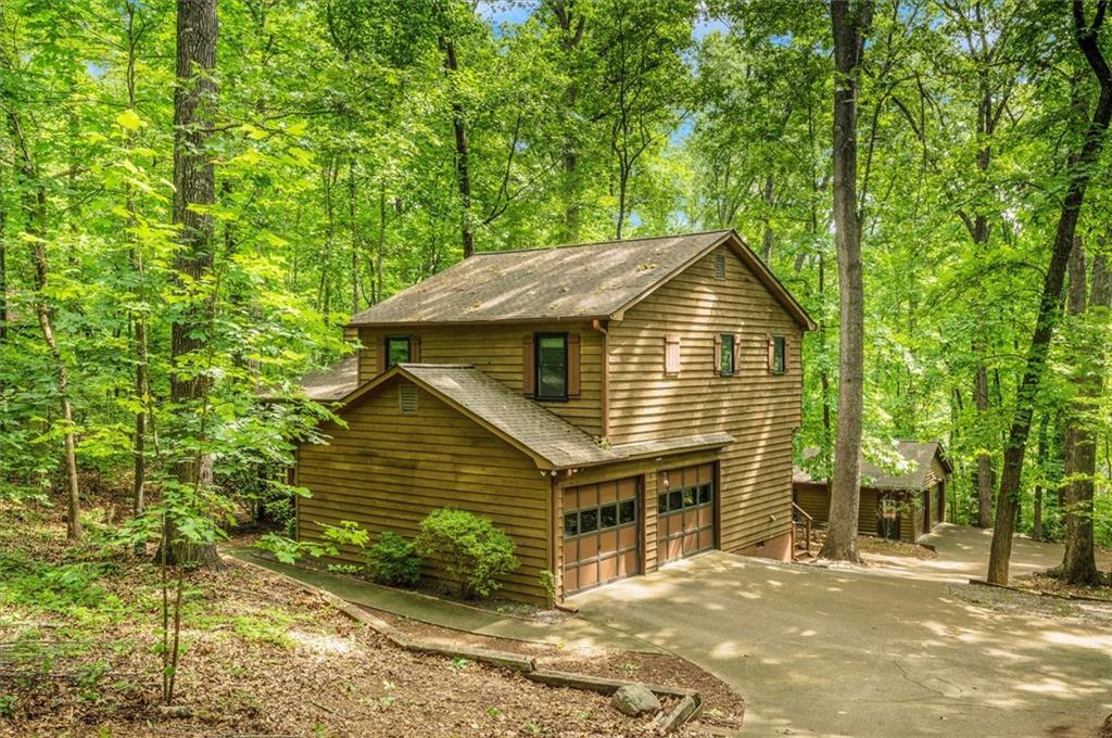 Discover this exceptional split-level home nestled on a serene 1.37-acre wooded lot in the coveted Sparrow Ridge subdivision, located within the top-rated Lassiter High School cluster. Built in 1984, this meticulously maintained residence offers 3 bedrooms, 2.5 baths, and approximately 1,384 square feet of thoughtfully upgraded living space. Including brand new windows and sliding glass doors installed by Champion, as well as new plumbing throughout the home. Step onto the welcoming front porch and into a cozy great room featuring a striking stone fireplace, rich wood-grain flooring, and abundant natural light. The adjacent eat-in kitchen is equipped with ample cabinetry and a convenient powder room and laundry nearby. Sliding glass doors open to an expansive deck overlooking a tranquil backyard with a firepit—perfect for outdoor entertaining or quiet evenings under the trees. Upstairs, the spacious primary suite includes a private bath, while two additional bedrooms share a well-appointed hall bathroom. Parking and storage are exceptional, with an attached 2-car garage and a fully finished 25×25 detached garage/workshop complete with 220V service and space for six vehicles or RV turnaround. With no HOA and a peaceful, private setting, this rare opportunity offers the perfect blend of comfort, functionality, and seclusion.